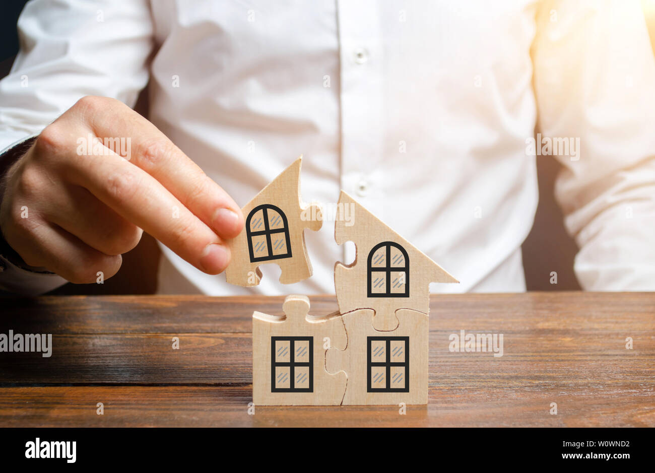 A man collects a house of puzzles. Construction of your own residential building. Mortgage loan, residential expansion and improvement of living condi Stock Photo