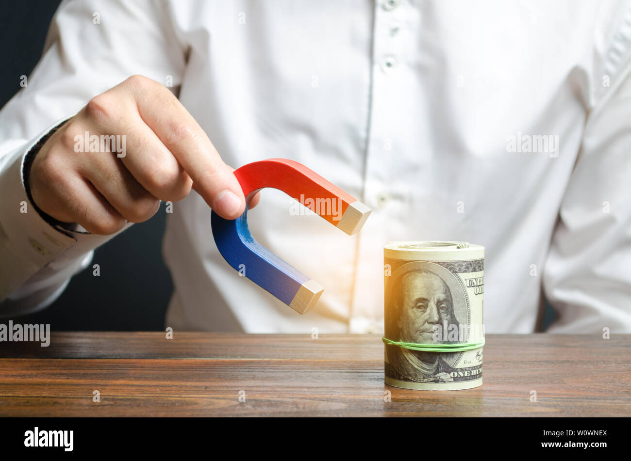 Businessman attracts money with a magnet. Attracting money and investments for business purposes and startups. Increase profits and attract new custom Stock Photo