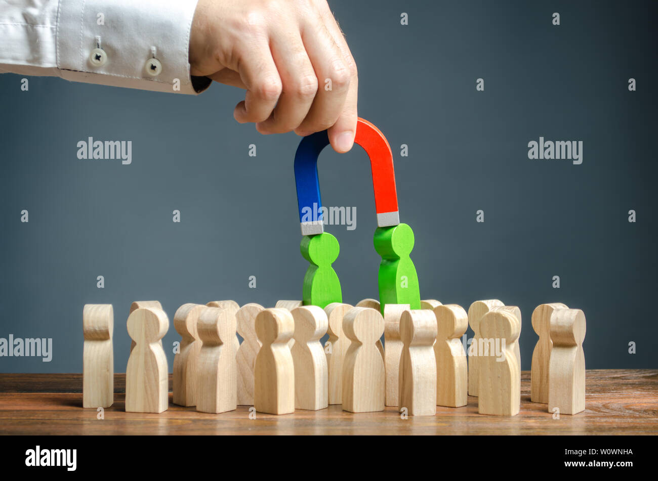 Businessman with a magnet pulls green figures of people out of the crowd. Recruiting new workers. Formation of a new business team of applicants. Sear Stock Photo