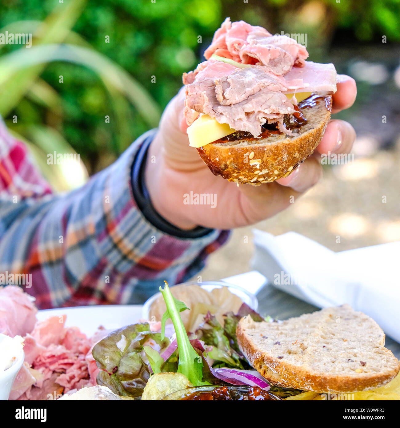 Man Holding A Fresh Ploughmans Salad Bread Roll Filled With Cheese
