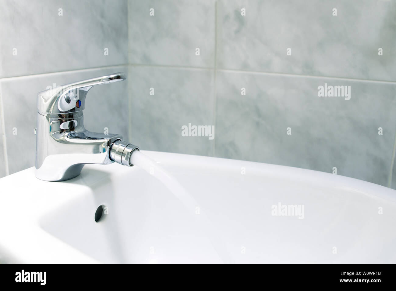 Detail of the faucet of a bidet with running water.The bidet was