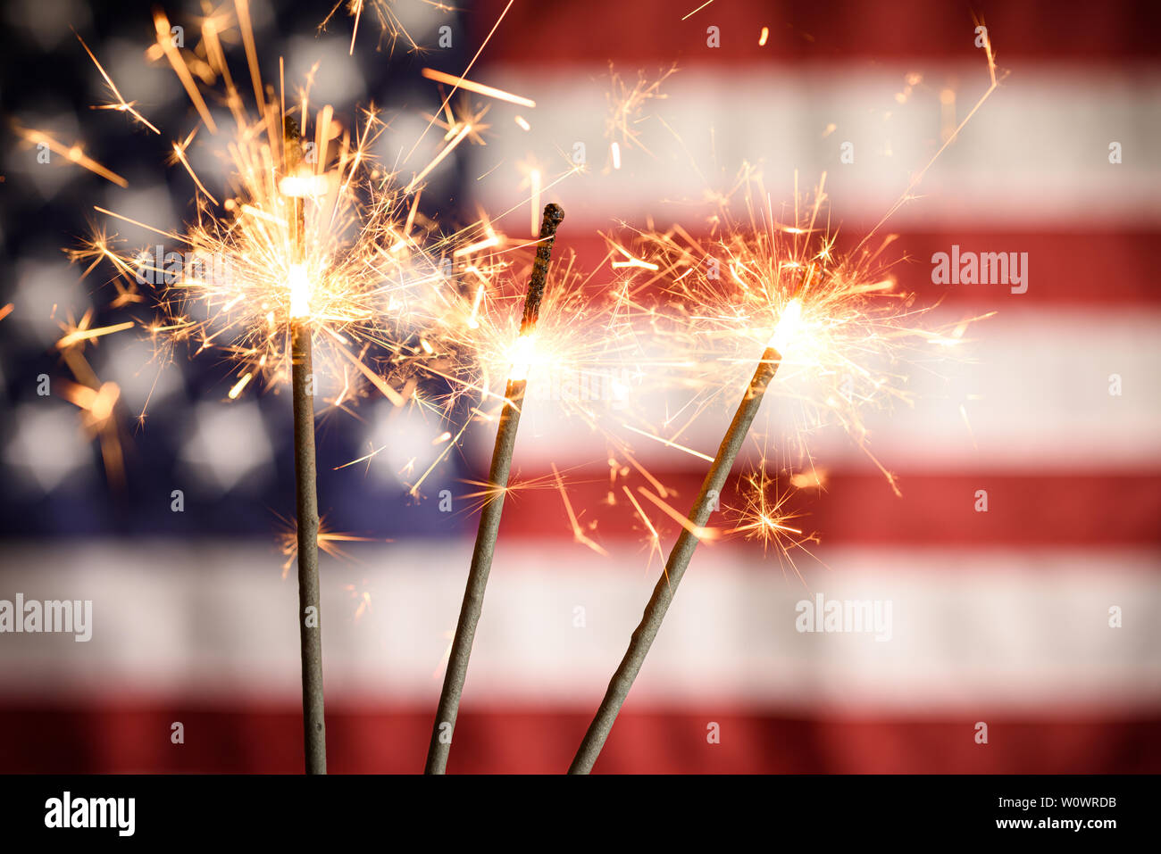 Sparklers Closeup With American Flag In Background. Celebrating 4th Of July Independence Day Stock Photo