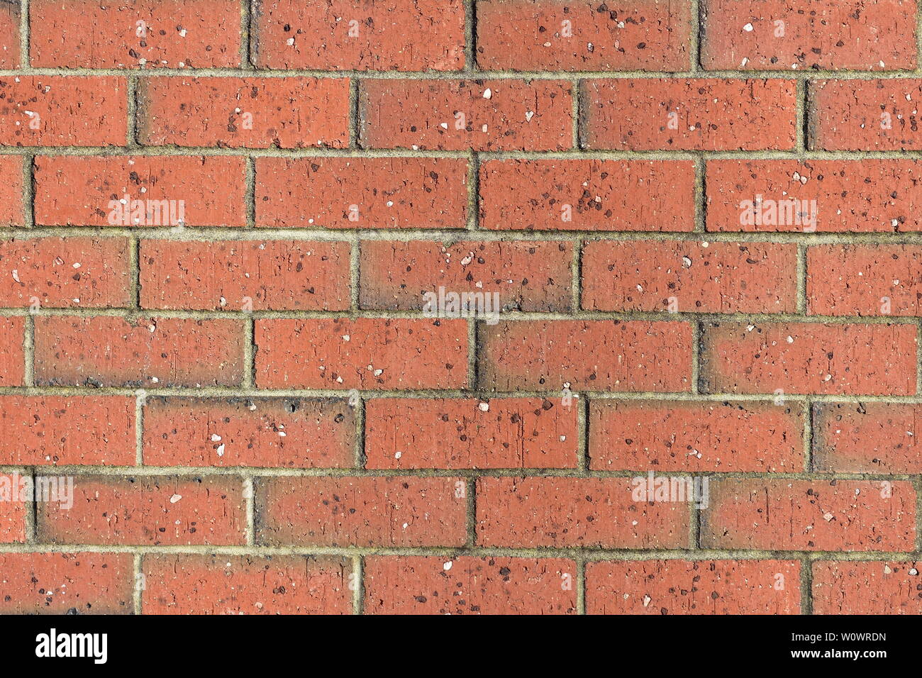 Red brick wall pattern with unevenly distributed small rock chips in ...