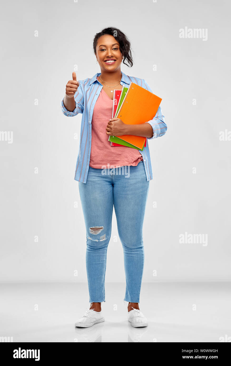african student with notebooks showing thumbs up Stock Photo - Alamy