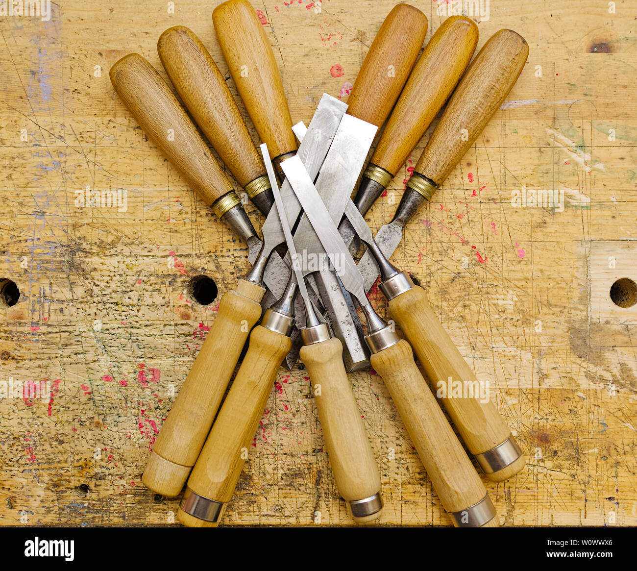 Group of assorted woodworking chisels isolated on wooden bench grunge surface. Stock Photo