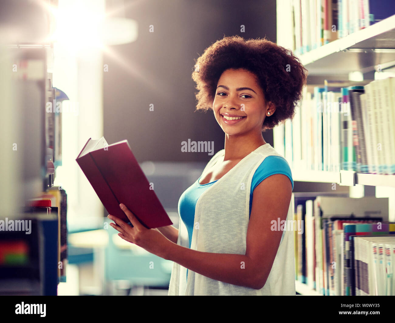 happy african student girl reading book at library Stock Photo - Alamy