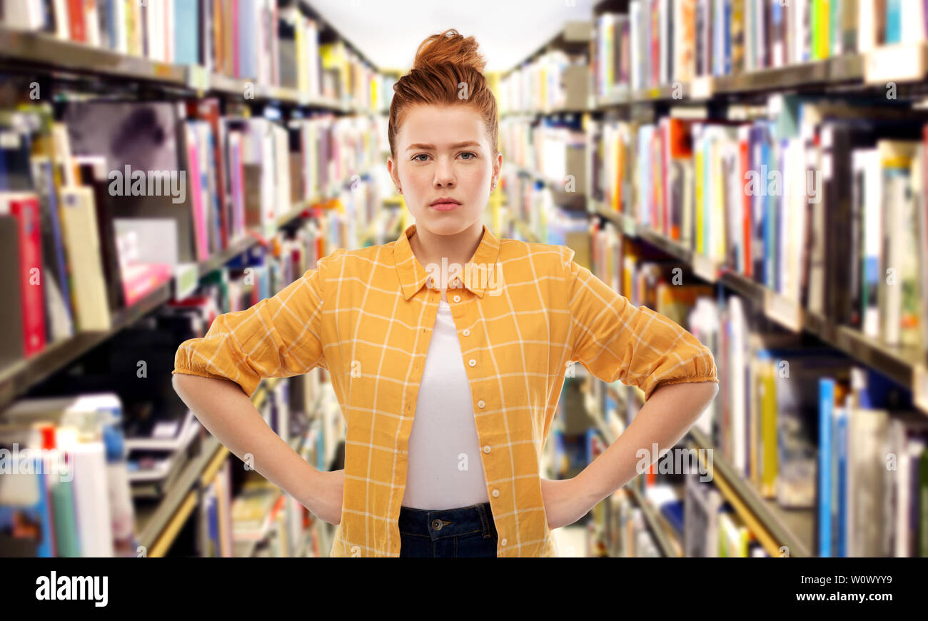 displeased red haired student girl at library Stock Photo