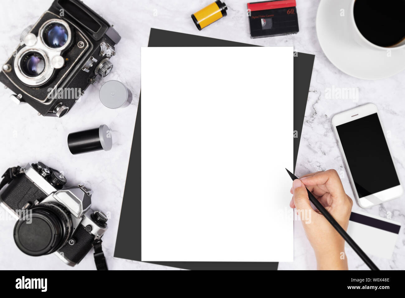 flat lay hand writing in a blank white page notebook decorated with vintage camera and photography tool on white marble background Stock Photo