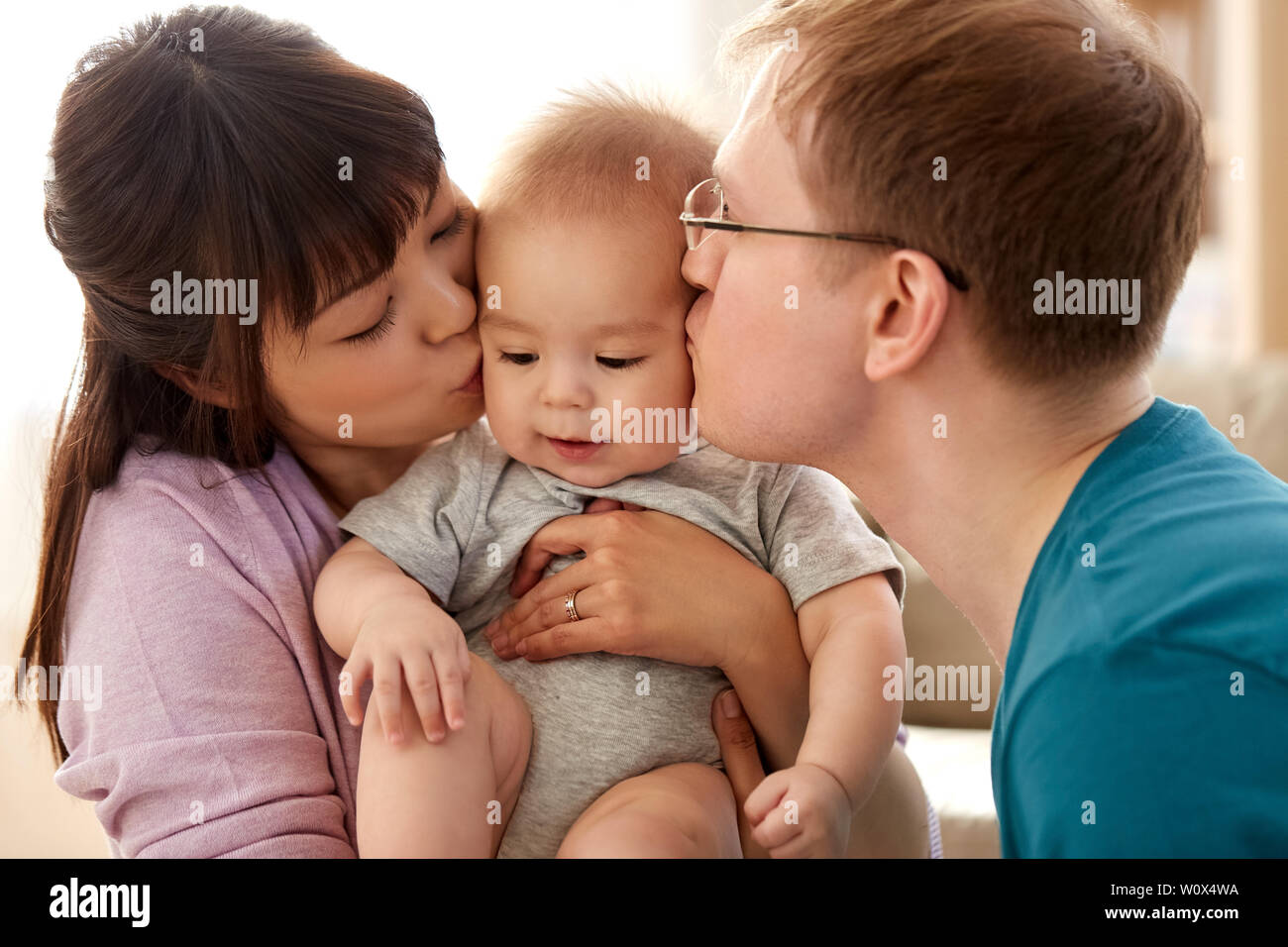happy mother and father kissing baby son at home Stock Photo
