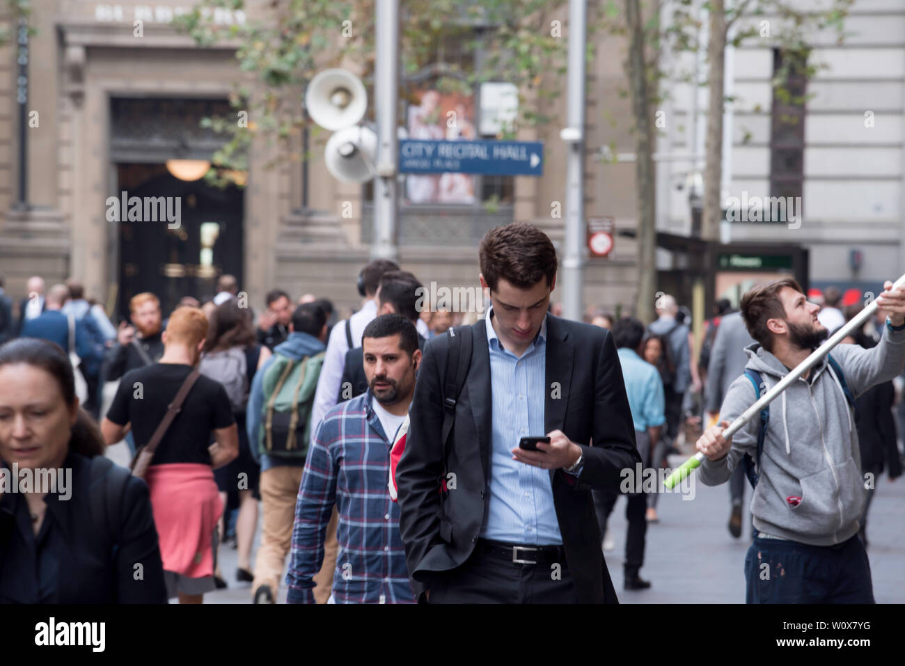 A window cleaner works as peak hour commuters walk along the Sydney CBD