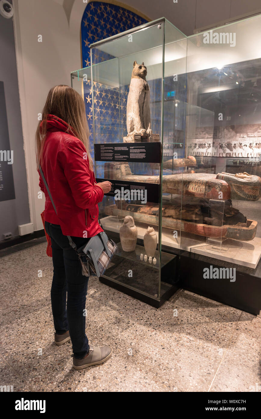Egyptian cat mummy, rear view of a young woman looking at an ancient Egyptian cat sarcophagus in the Oslo Historical Museum, Norway. Stock Photo