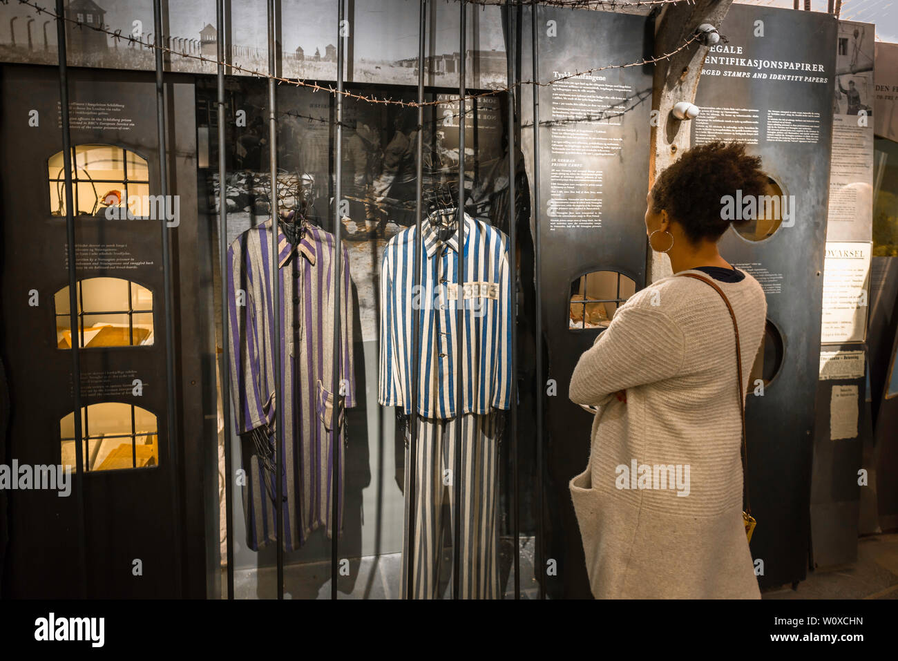 View of a woman looking at clothes worn by Nazi concentration camp inmates on display in the Norwegian Resistance Museum in central Oslo, Norway. Stock Photo