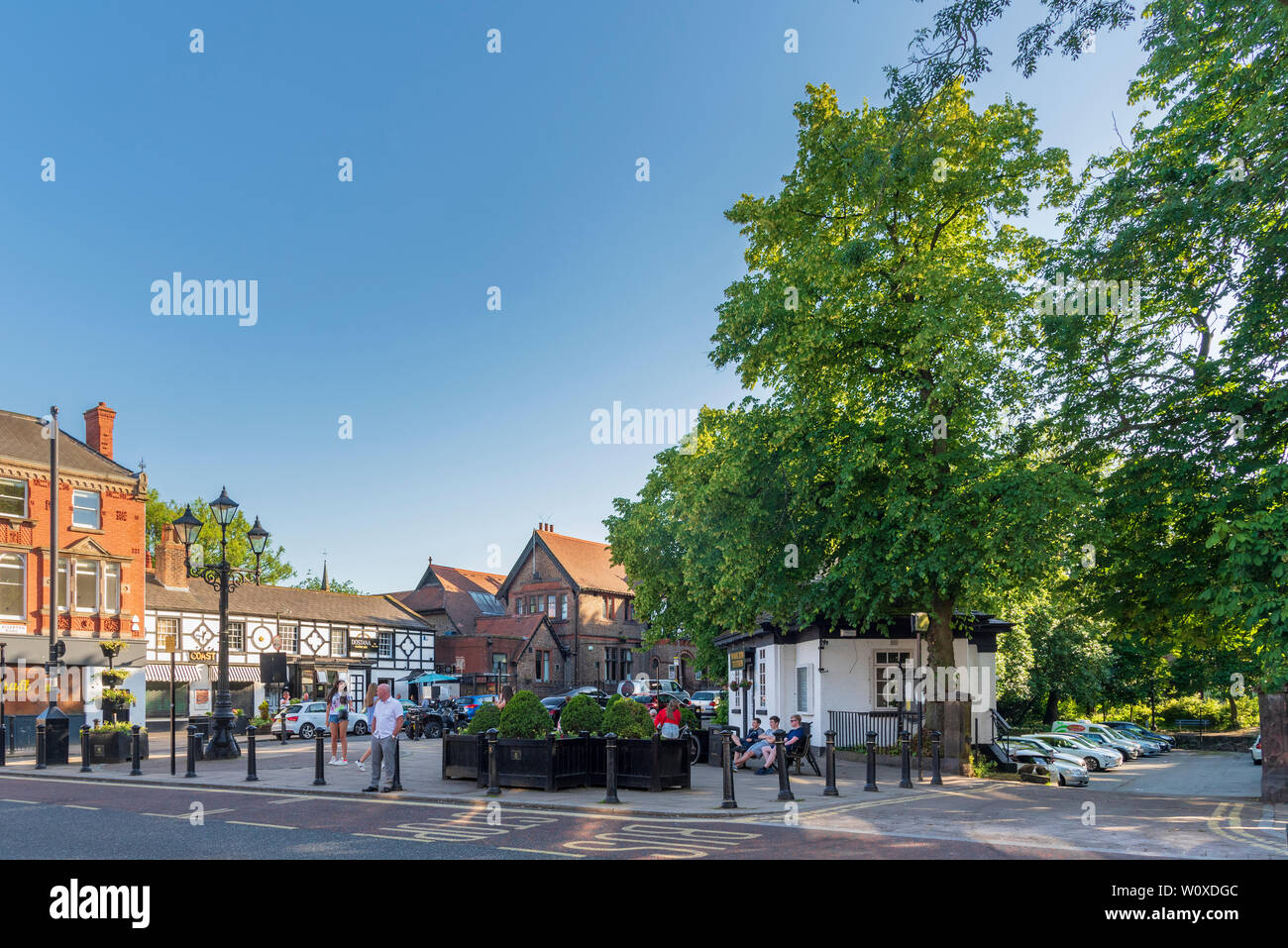 The centre of Woolton village Liverpool on a summers evening wit the former public convenience turned into offices and former duck pond now a car park. Stock Photo