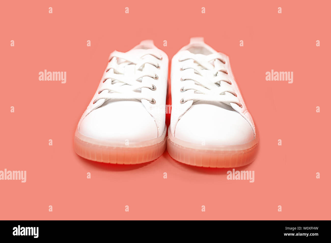 White sneakers are lying on a pastel pink coral background Stock Photo ...