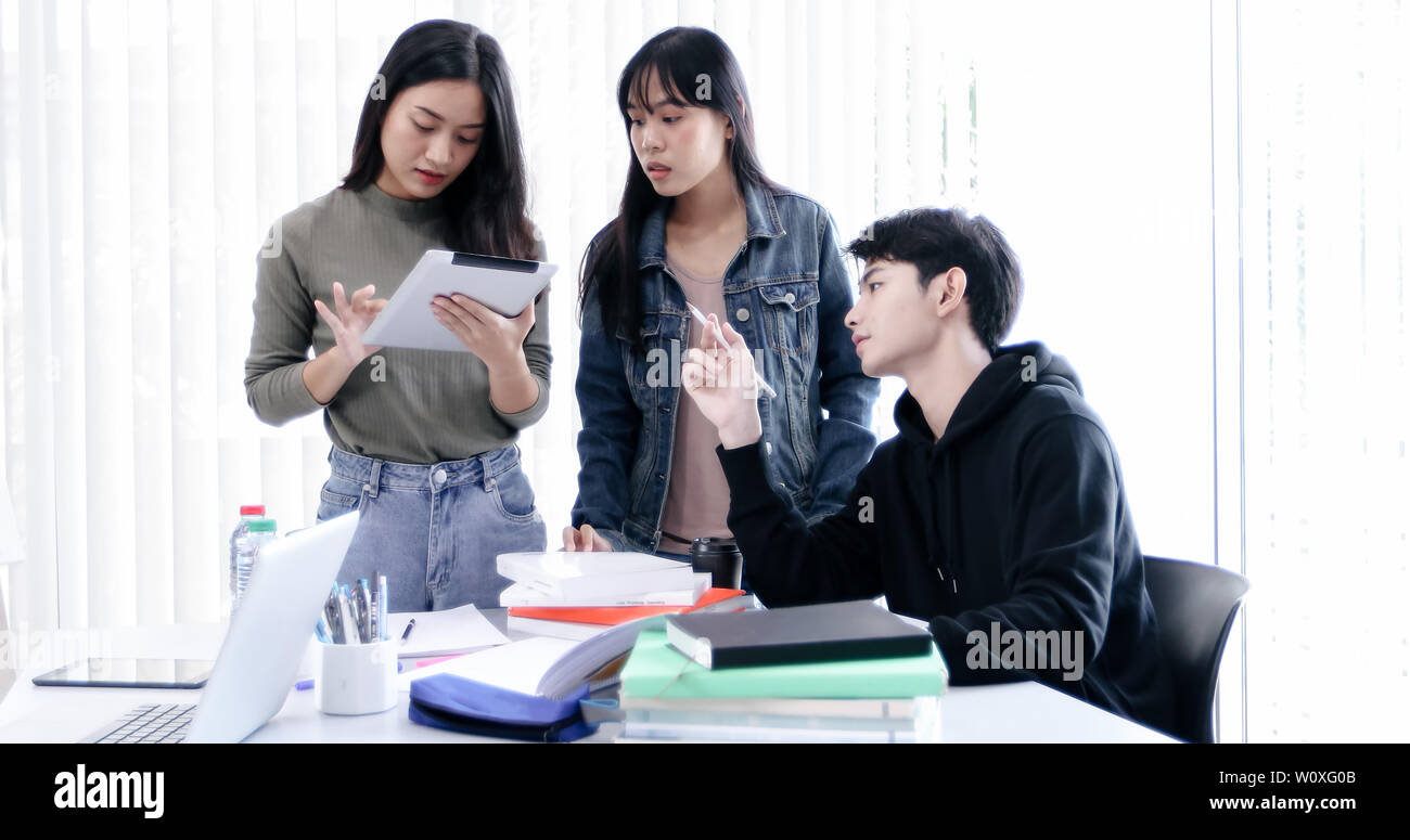 Group Students Smile and have fun and using tablet It also helps to share ideas in the work and project. And also review the book before the exam Stock Photo