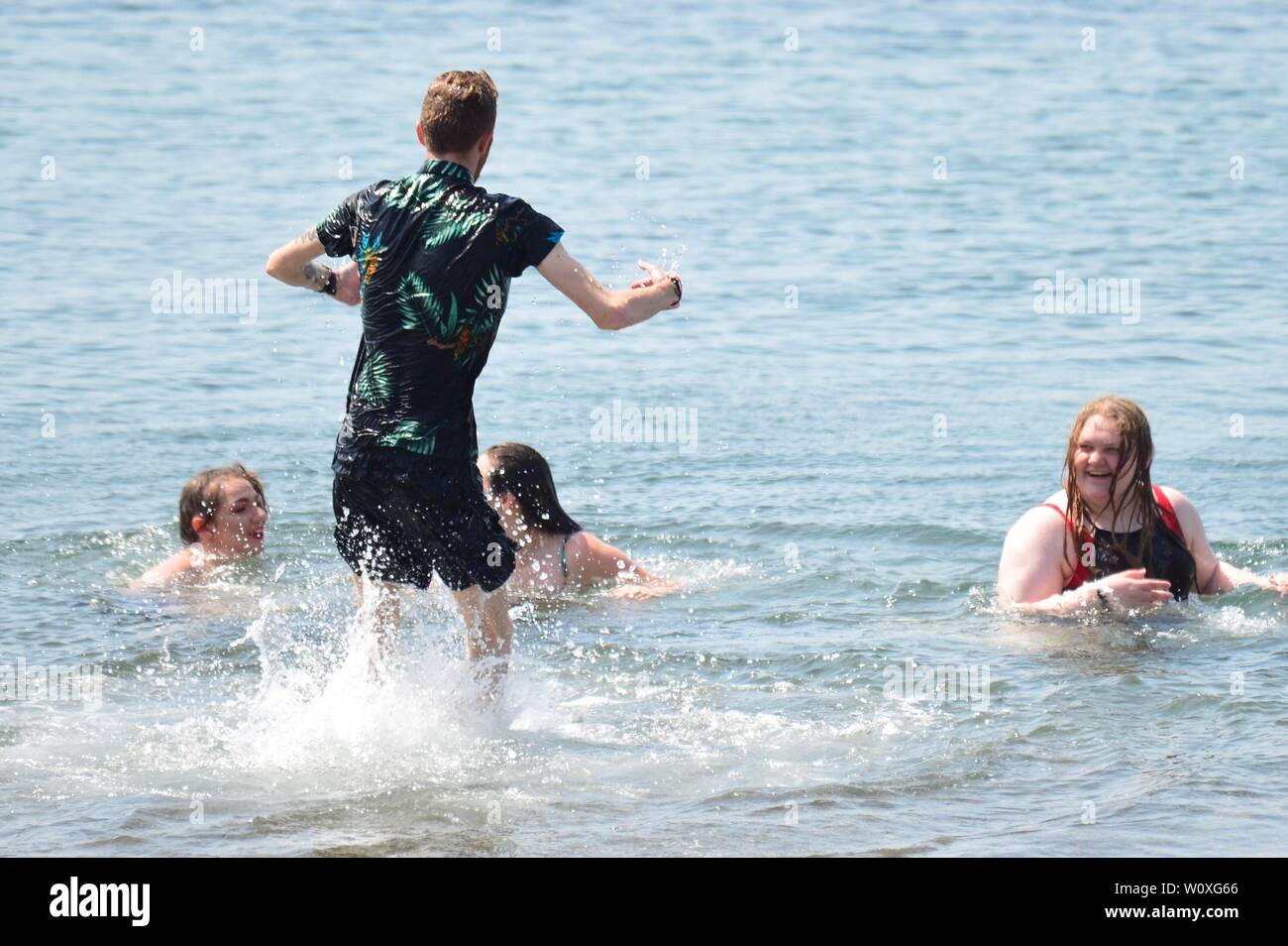 Aberystwyth, Wales, UK. 28th Jun 2019. UK weather: People at the seaside in Aberystwyth enjoying a day of unbroken blue skies and hot sunshine. The country is heading towards the hottest day of the year so far as a plume of scorching hot air drifts in from the continent. Photo Credit: keith morris/Alamy Live News Stock Photo