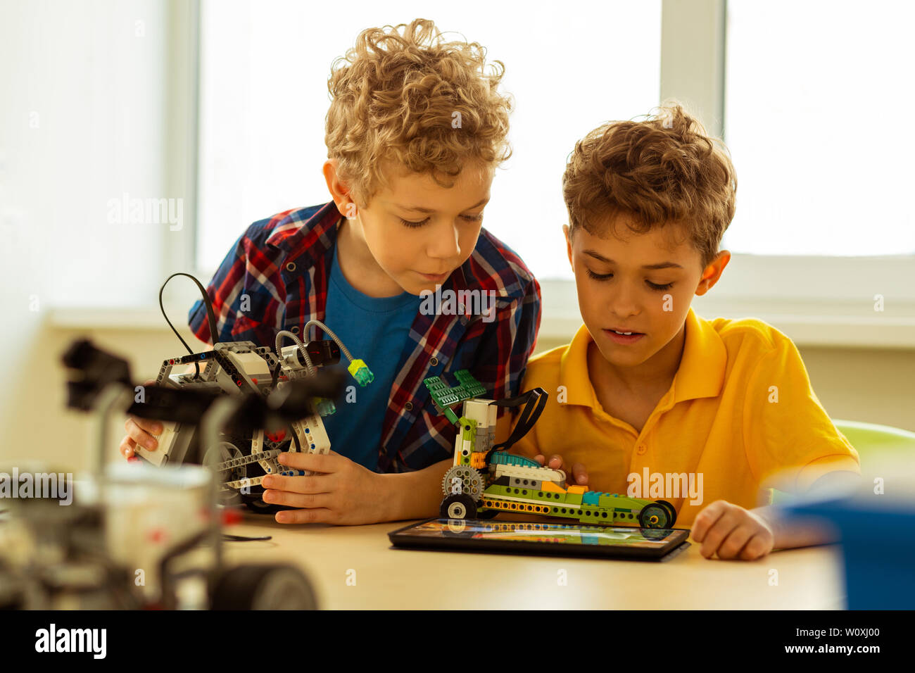 How to construct. Nice serious boy looking at the scheme while constructing a car according to it Stock Photo