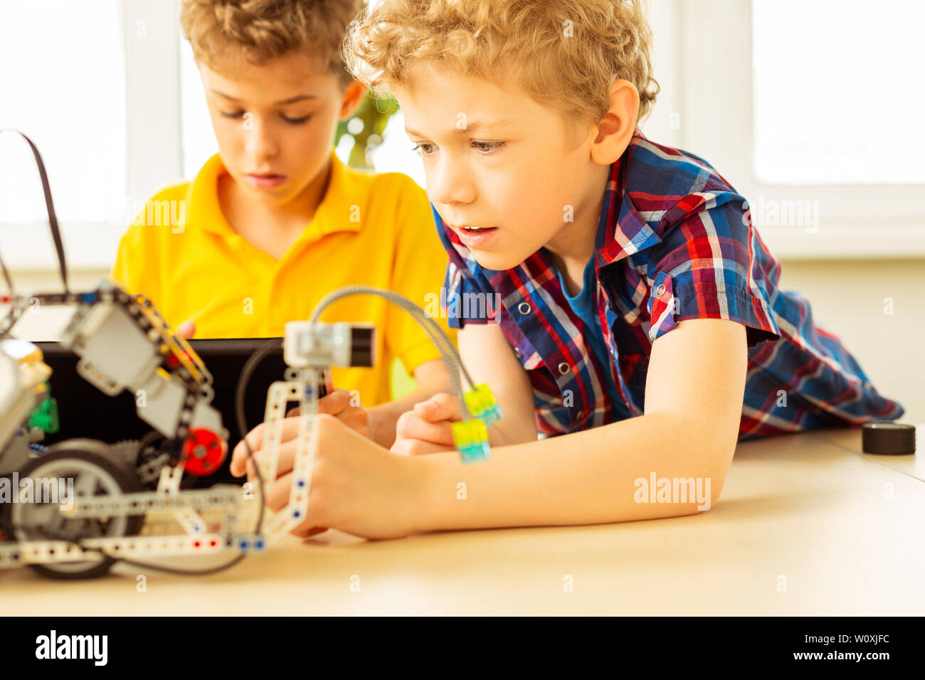 Science class. Smart blonde boy trying to construct a robot while ...