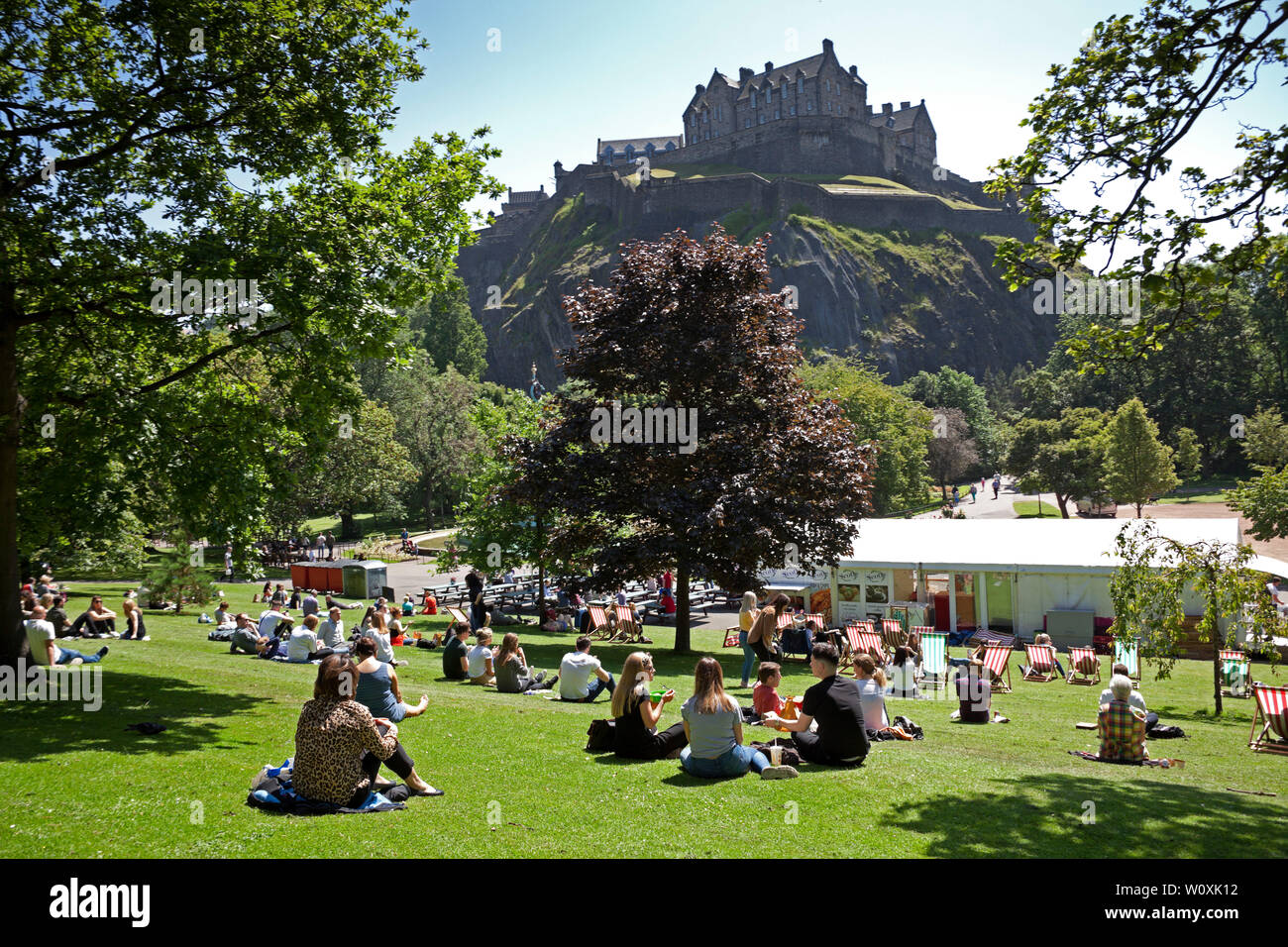 Princes Street Gardens Edinburgh, Scotland. 28th June 2019. Full sunshine in the city being enjoyed by office workers and visitors, 14 degrees in the morning with cool  wind increasing to 17 degrees in the afternoon allowing a relaxing lunch hour sunbathe. Stock Photo