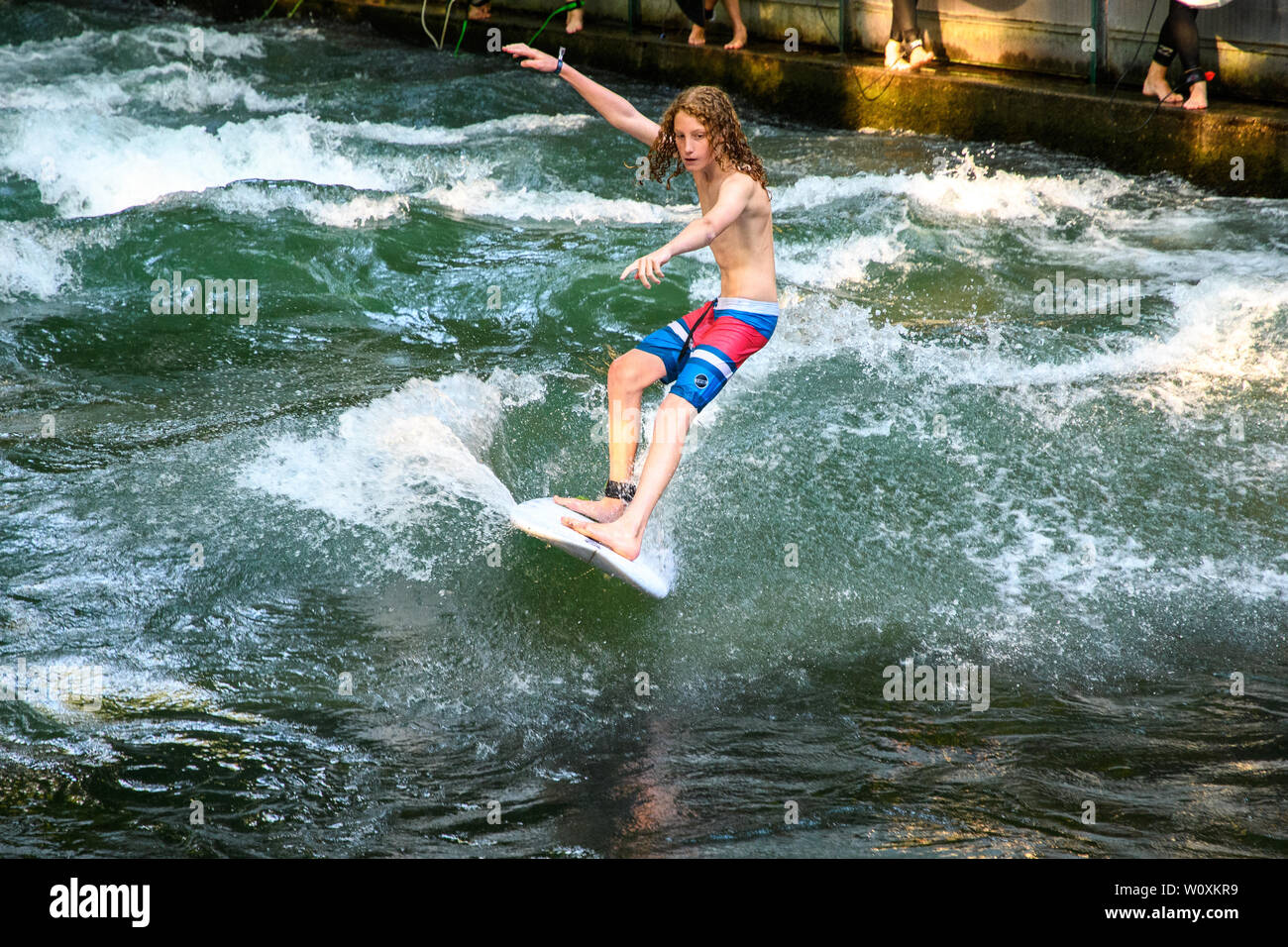 MUNICH, GERMANY - August 2018: Surfers train on a standing wave in a stream in the city Park during the heat wave. Stock Photo