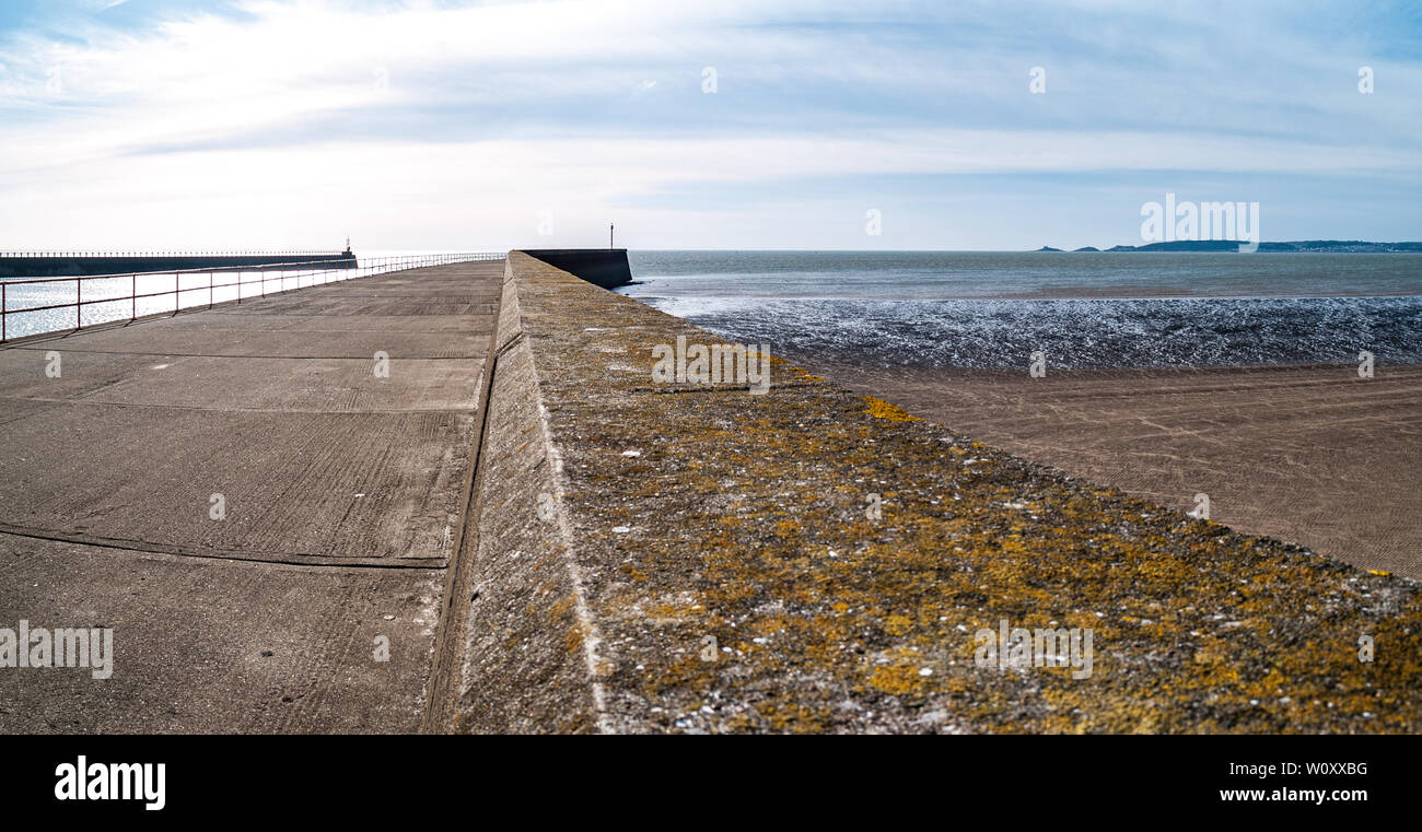 Beacons on the ends of the sea walls at the mouth of the river Tawe. Look out over Swansea Bay to Mumbles Point and lighthouse. Abertawe, Swansea, UK. Stock Photo