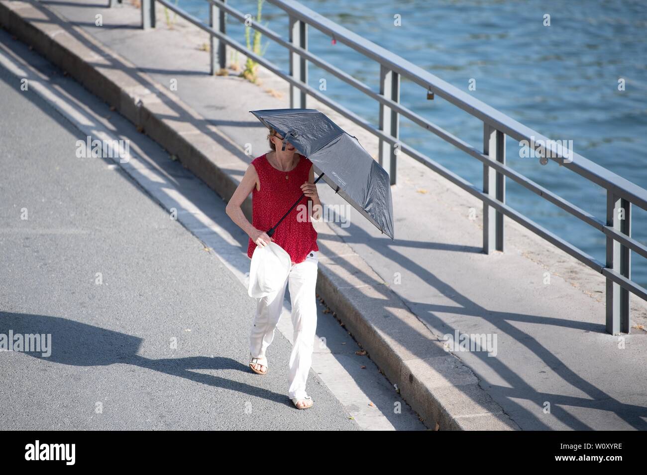 Paris, France. 27th June, 2019. A woman walks with a sunshade in Paris, France, June 27, 2019. The national weather center, Meteo France, on Thursday warned of "exceptional heat peak" on June 28, placing 4 southern regions on red alert, the highest alert on the agency's four-scale system, and urges residents to be extremely vigilant. While 76 other regions, except Brittany, in northwest France, remain on orange alert till next week. Credit: Jack Chan/Xinhua/Alamy Live News Stock Photo
