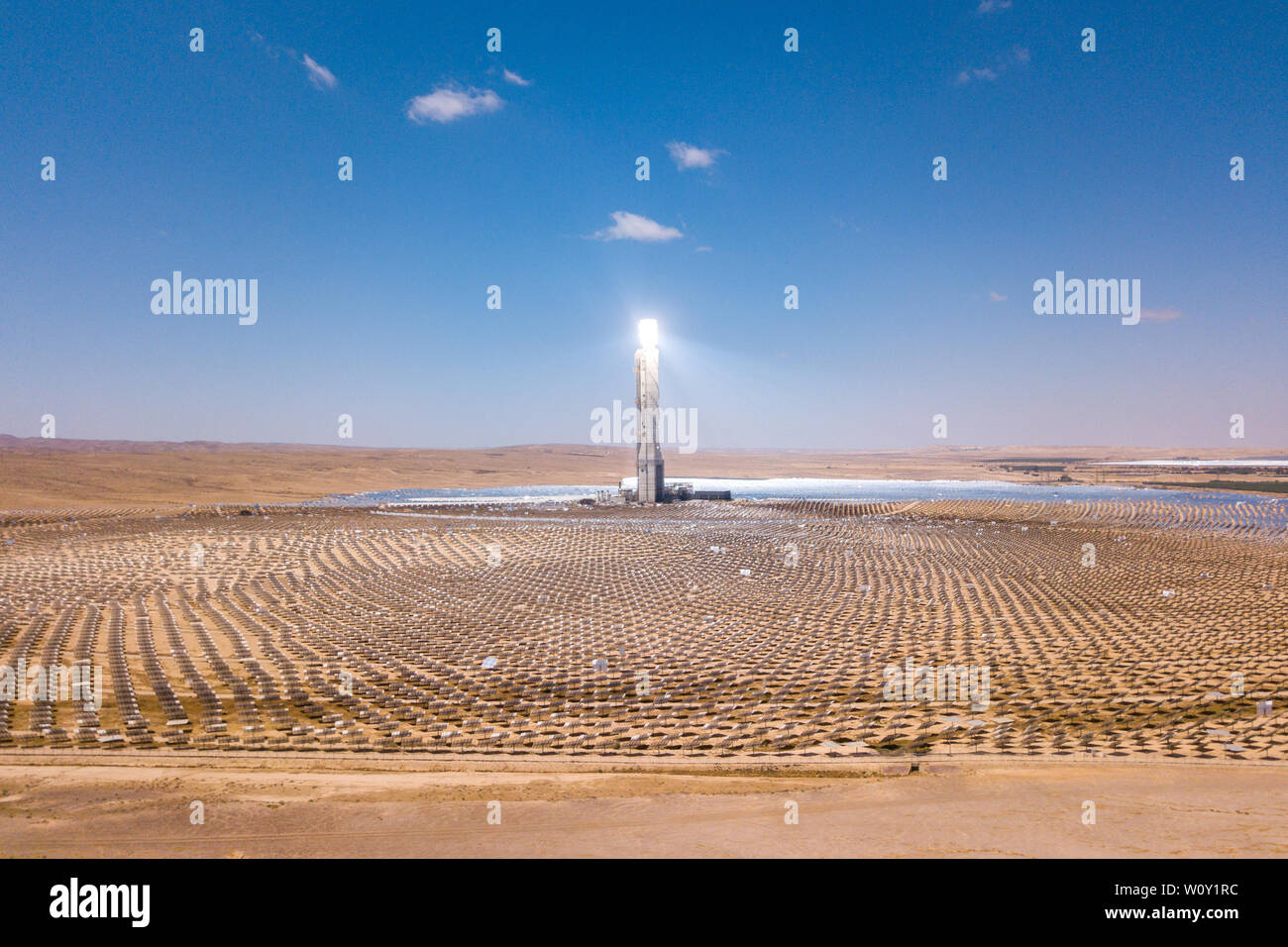 Solar power tower and mirrors that focus the sun's rays upon a collector tower to produce renewable, pollution-free energy, Aerial image. Stock Photo