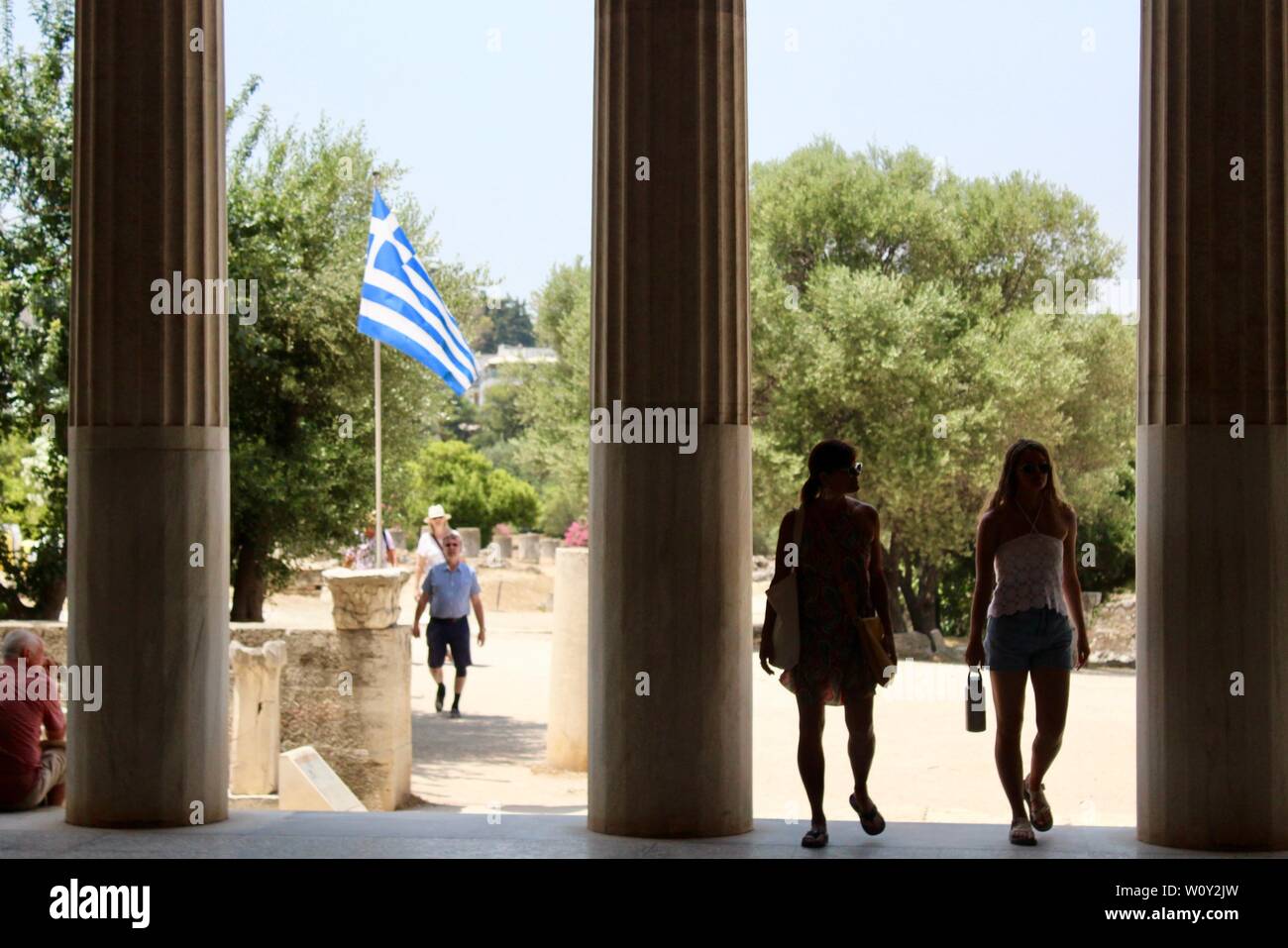 Ancient Agora of Athens two women near pillars and greek flag greece Stock Photo