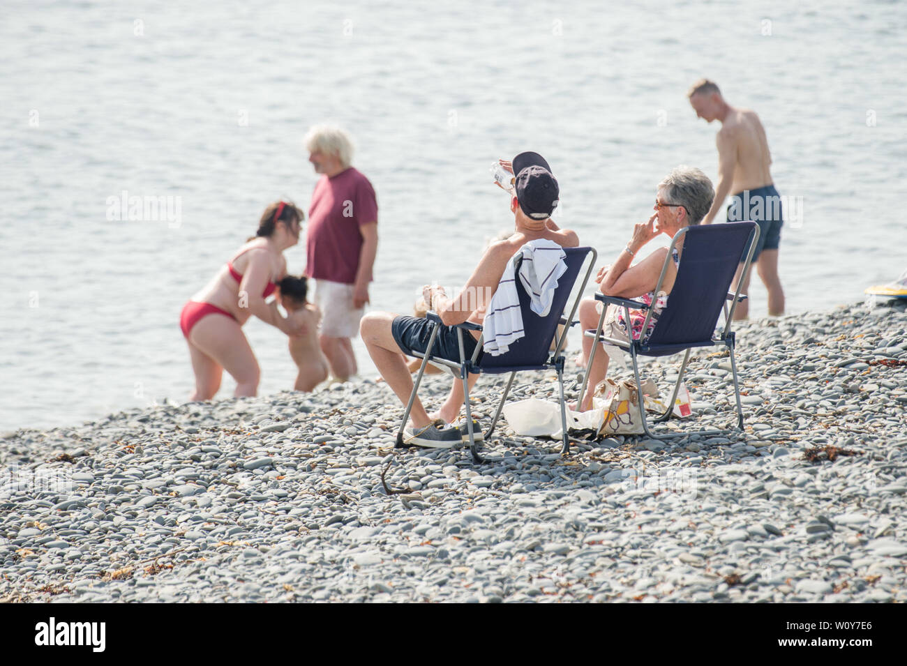 Aberystwyth, Wales, UK. 28th Jun 2019. UK weather: People at the seaside in Aberystwyth enjoying a day of unbroken blue skies and hot sunshine. The country is heading towards the hottest day of the year so far as a plume of scorching hot air drifts in from the continent.   Photo Credit: keith morris/Alamy Live News Stock Photo