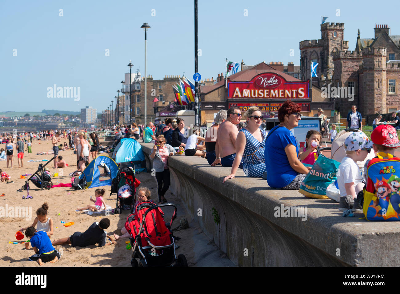Portobello, Scotland, UK. 28th June, 2019. Warm temperatures and unbroken sunshine brought hundreds of people and families to enjoy this famous beach outside Edinburgh. Promenade at Portobello is busy with families . Credit: Iain Masterton/Alamy Live News Stock Photo