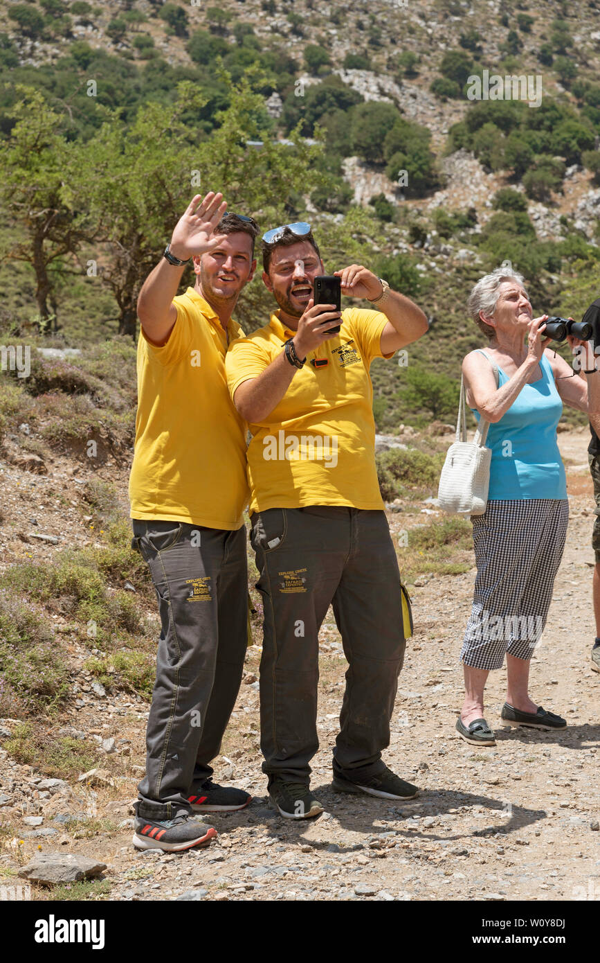 Crete, Greece, June 2019. Tour guides wearing yellow shirts working as a team and having fun with their tour group Stock Photo