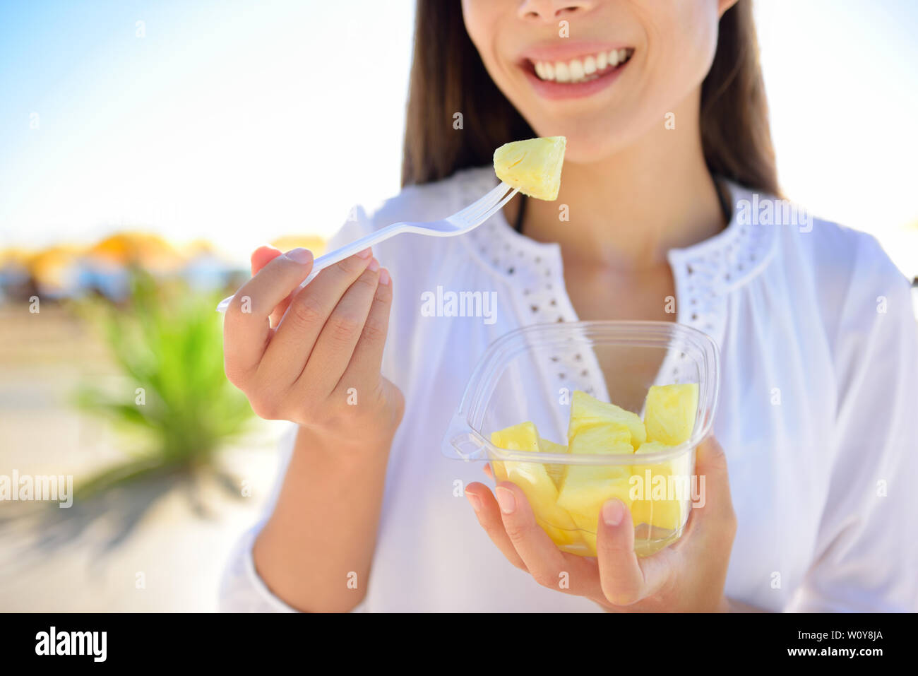Pineapple woman eating sliced Hawaiian pineapple fruit as a healthy