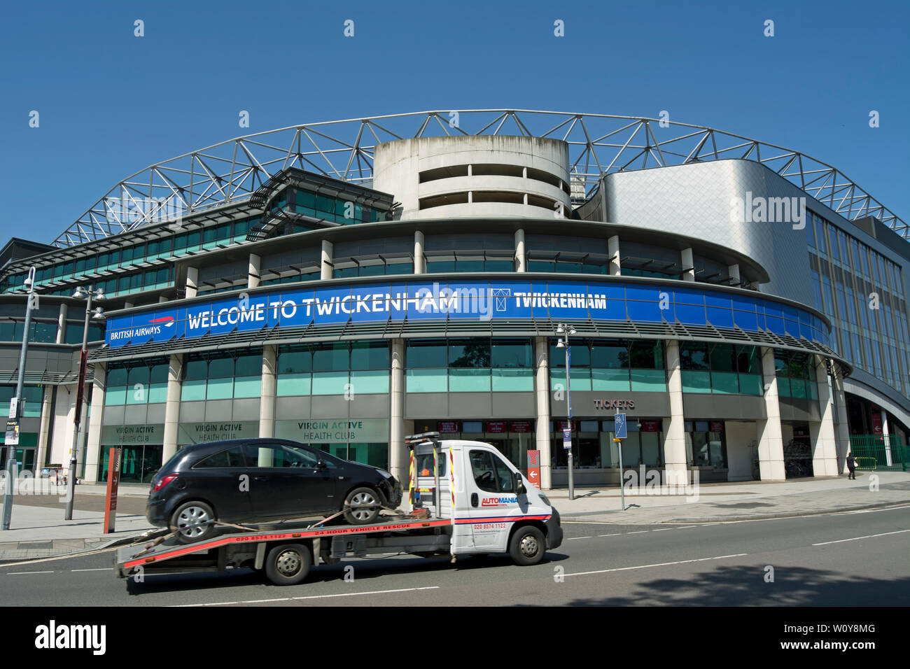 a tow truck carrying a car passes a welcome to twickenham sign at twickenham stadium, twickenham, middlesex, england Stock Photo
