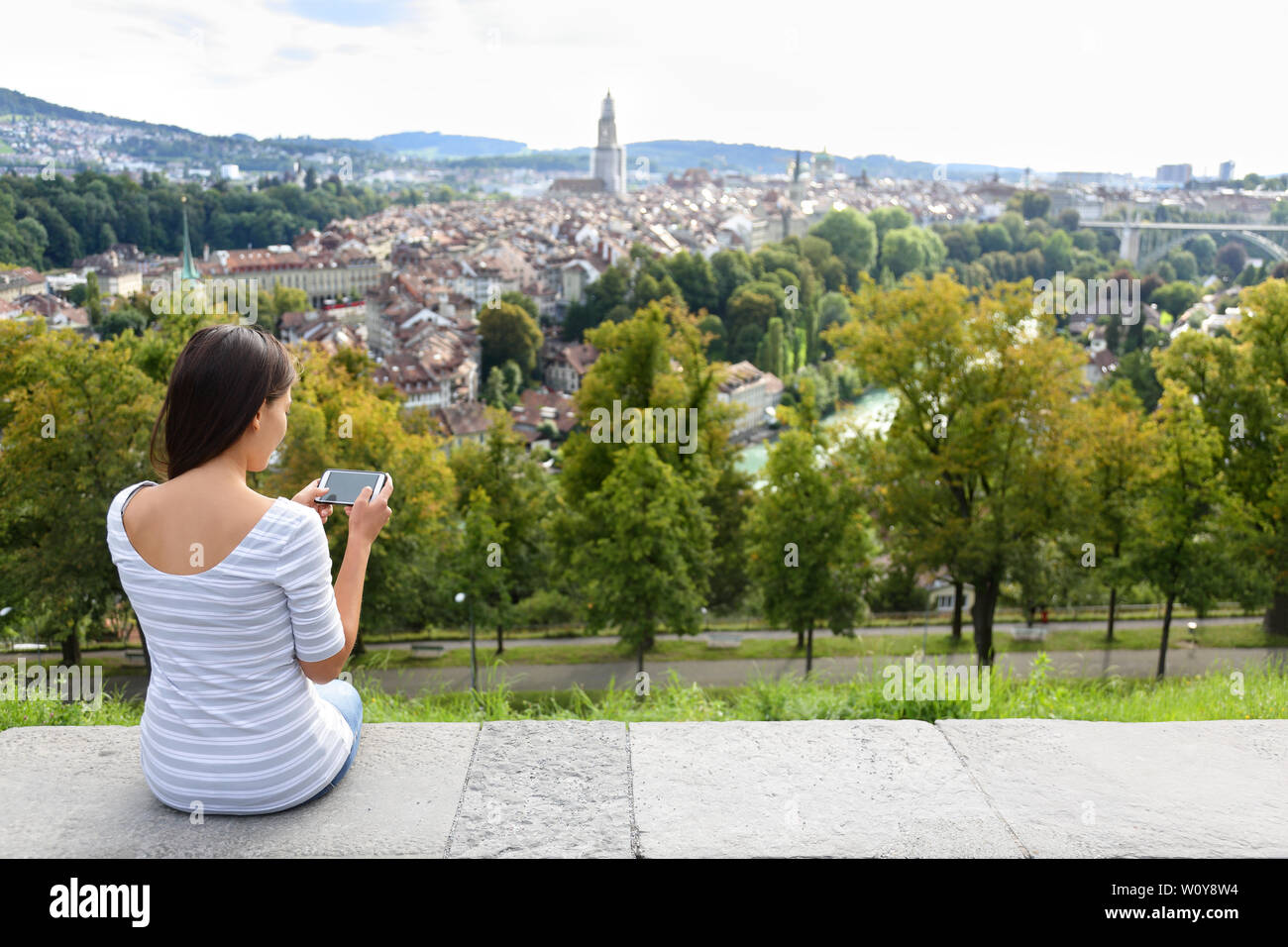 Tourist with smart phone camera in Bern, Switzerland at Rosengarten, the Rose Garden view. Woman taking photograph with smartphone at enjoying view of Berne landmarks and tourist attractions. Stock Photo