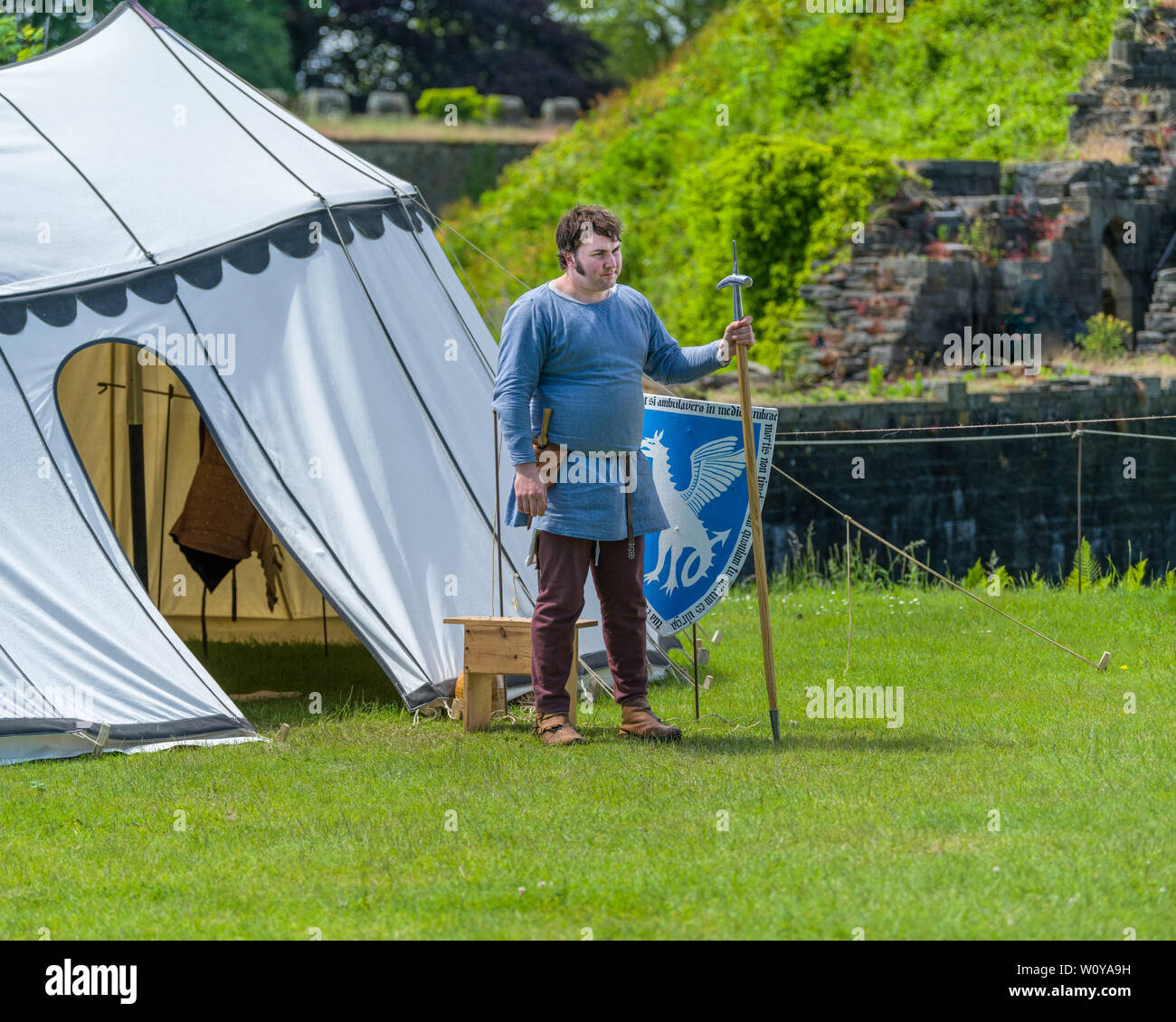 Medieval armorer stands by his shield. The encampment at Cardiff Joust 2019. Stock Photo