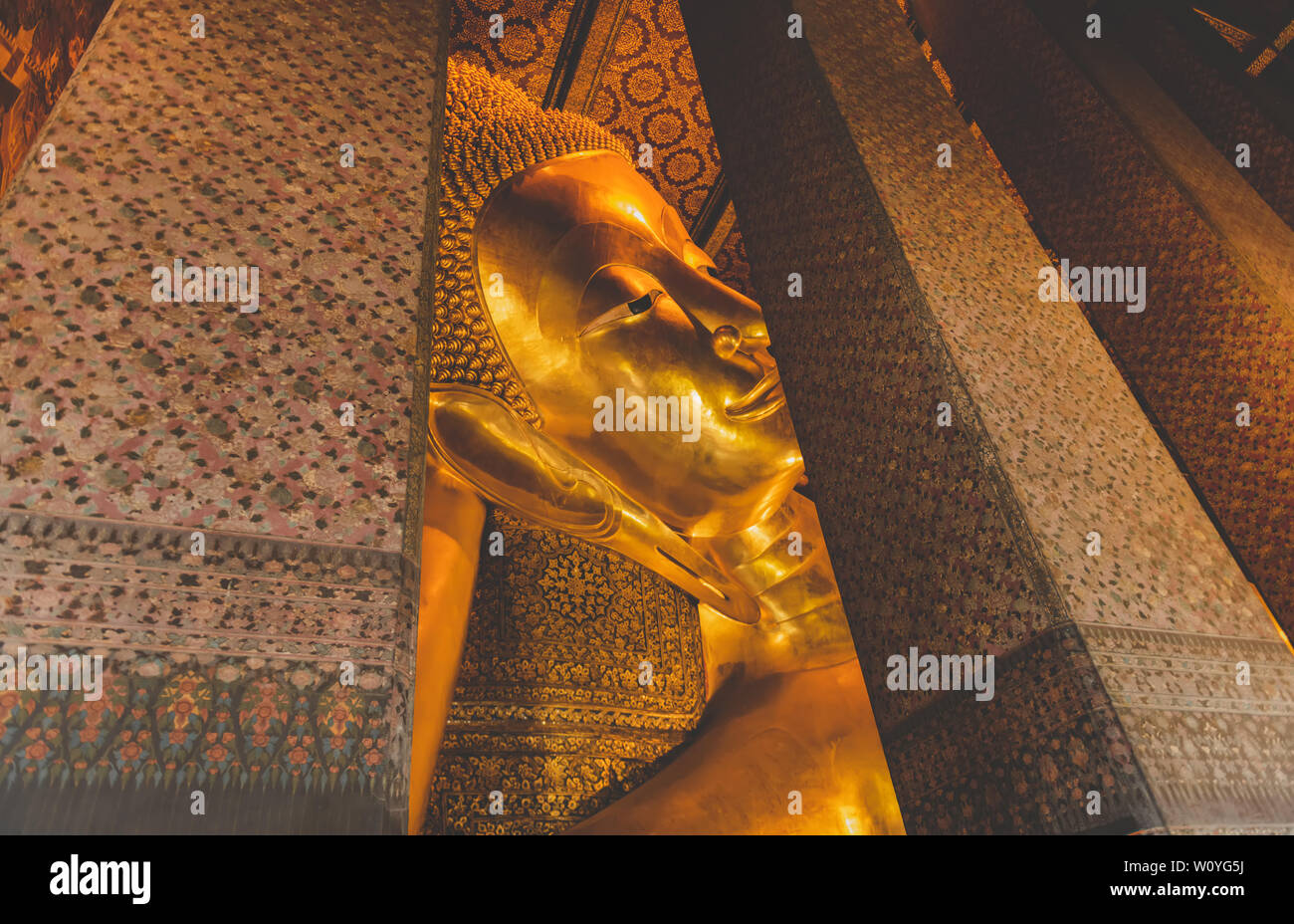 Sleeping golden Buddha statue ancient art of Thailand from Bangkok with warn sun lighting grey tone color. Stock Photo