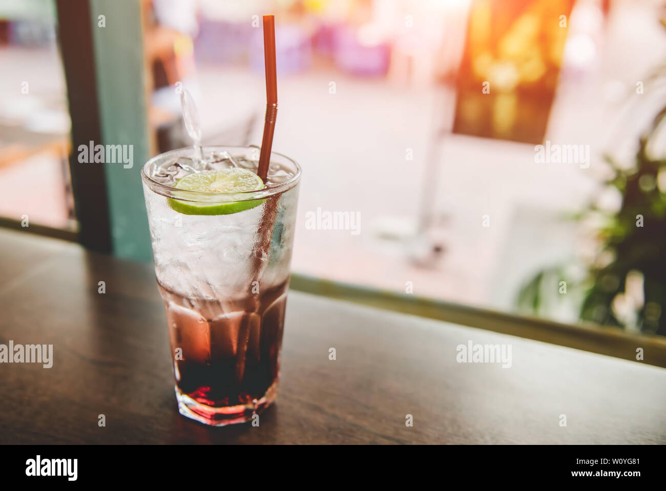 Ice and cold sweet soda drink with window low sun lighting. Stock Photo