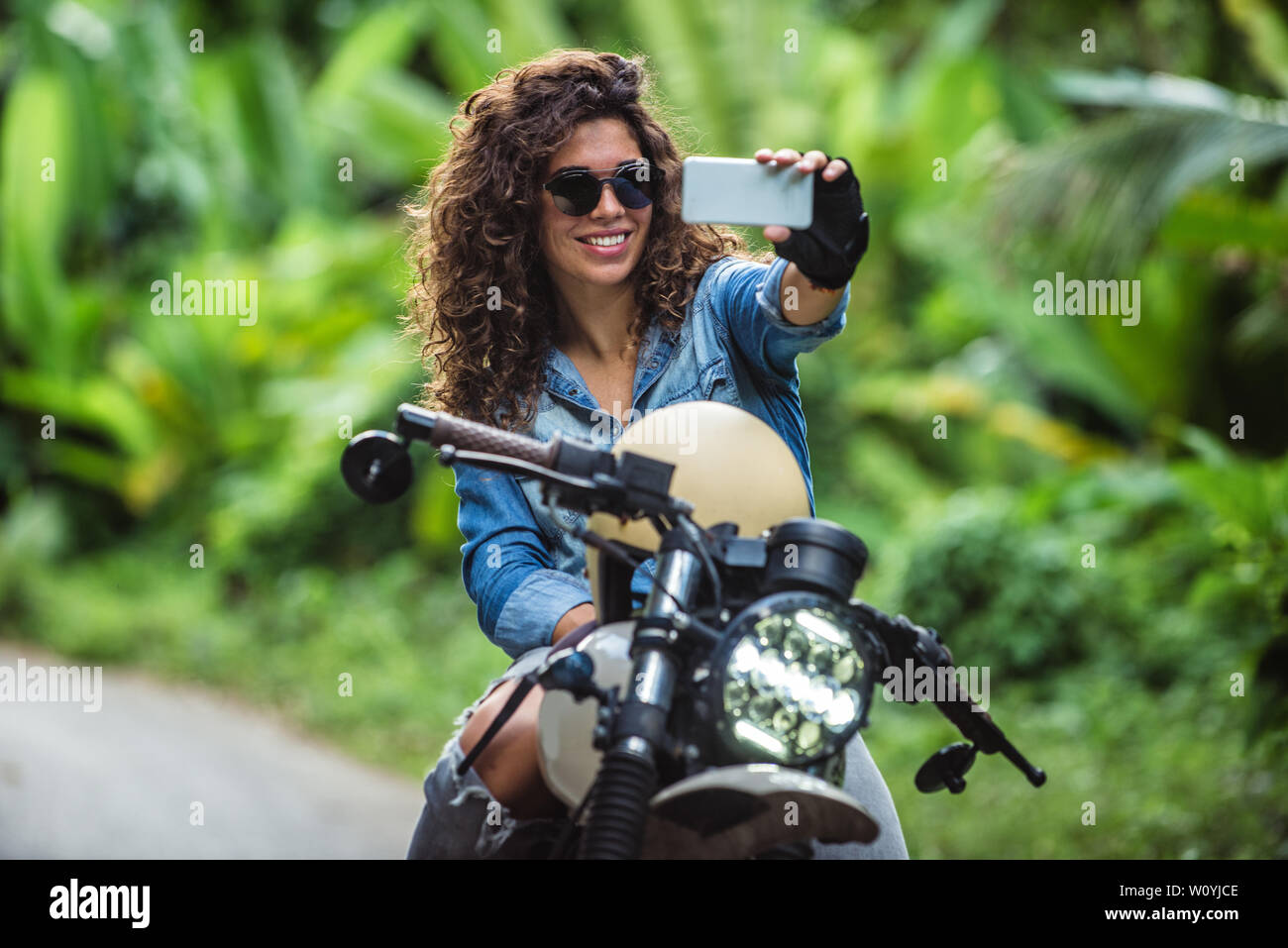 Beautiful female biker driving a cafe' racer motorbike Pretty girl