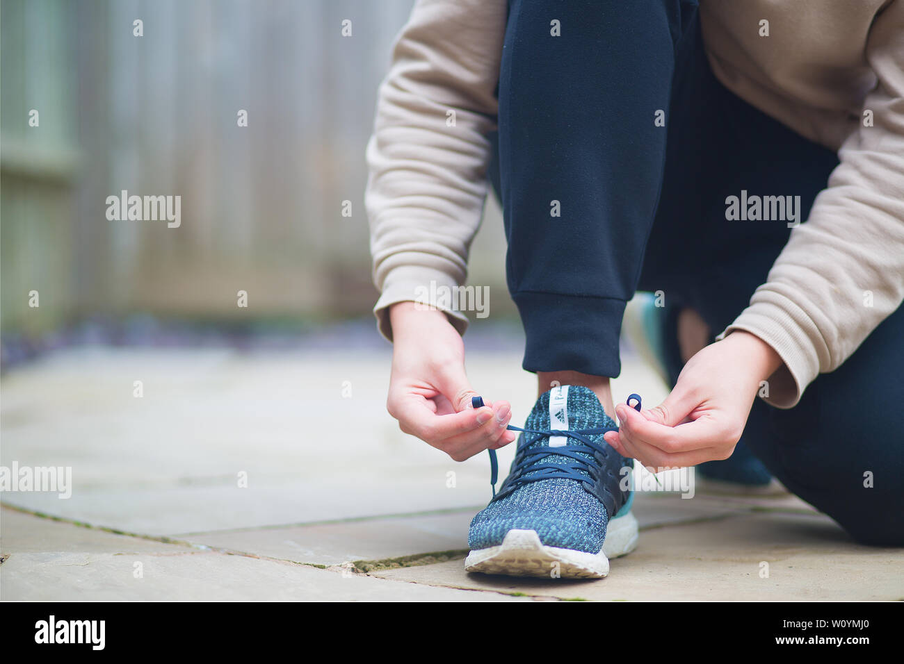 A man kneeling and tying his shoe laces Stock Photo