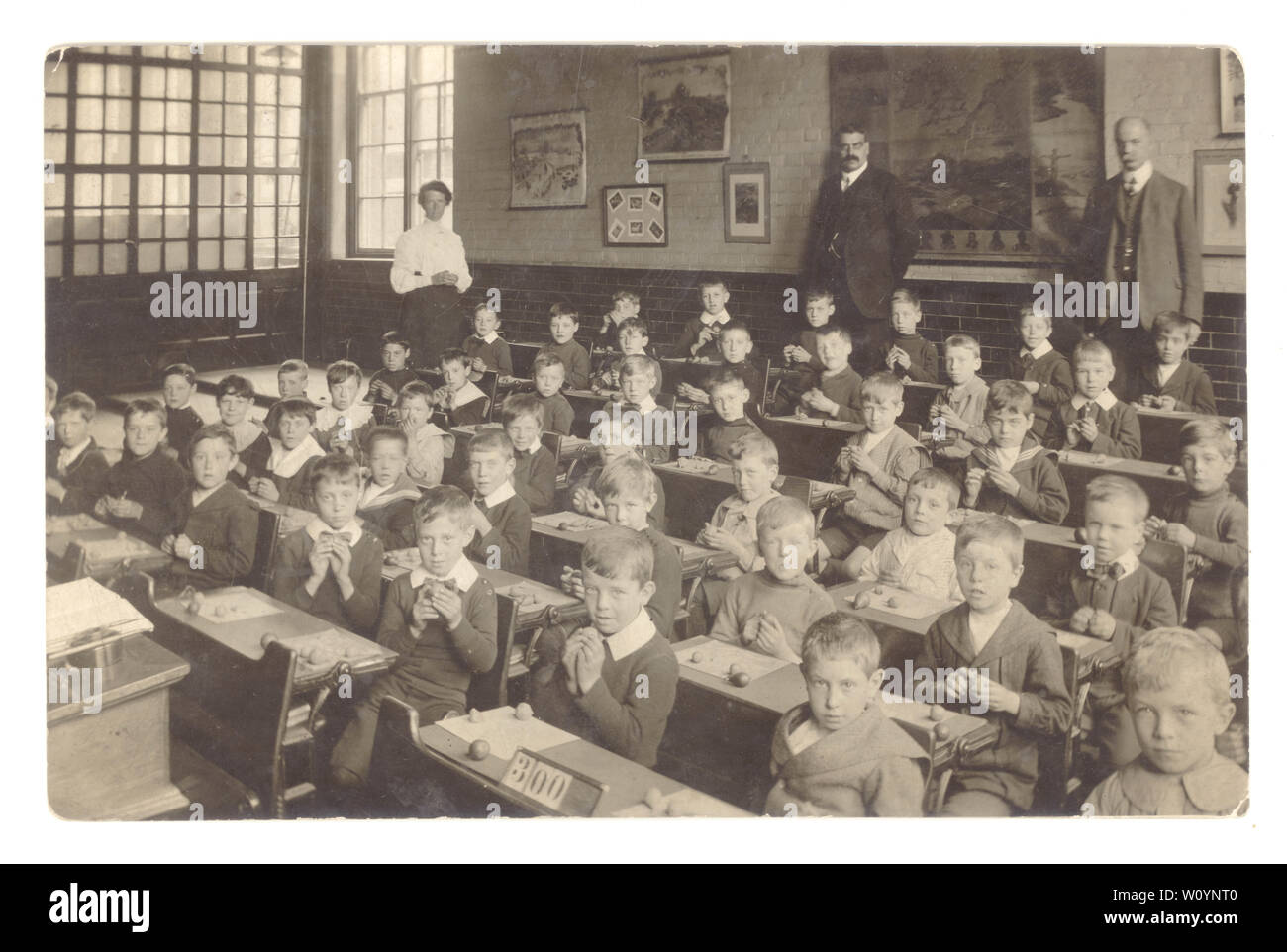 Edwardian postcard of junior or infant school boys in classroom wearing their Sunday best clothes, starched collars, modelling fruit with clay, male & female school teachers, school masters, U.K., circa 1910 Stock Photo