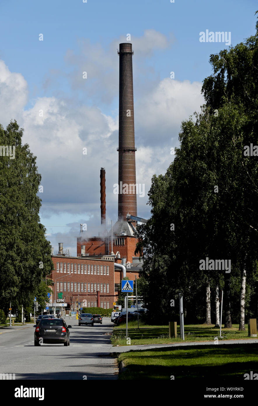 Pori Finland  06/27/2019 A street view with cars and UPM lumber industry. Factory steaming in the end  of the street Stock Photo