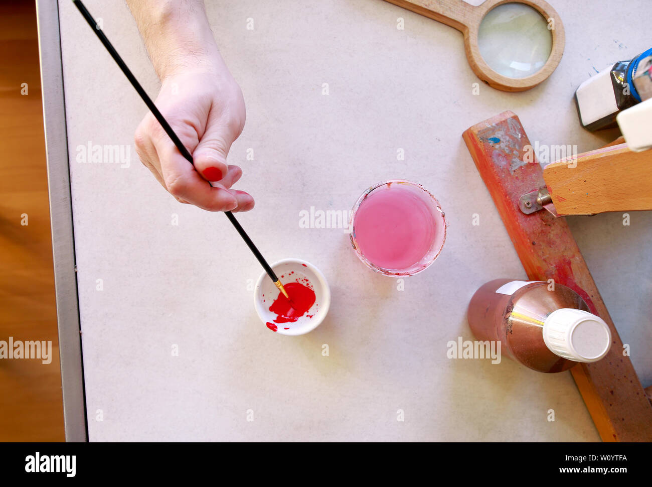 Man painter is mixing colors before painting at art paint studio. Artist in his hand holding