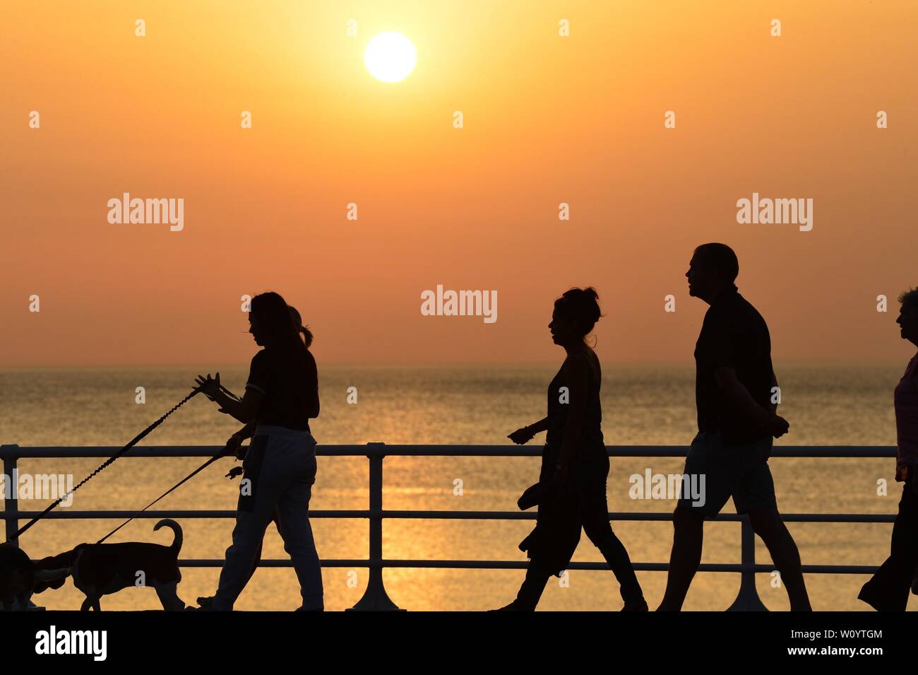 Aberystwyth, Wales, UK. 28th June 2019. UK weather: People on the  seaside pier at sunset in Aberystwyth on a sweltering summer  evening after a day of unbroken blue skies and hot sunshine. The country is heading towards the hottest day of the year so far as a plume of scorching hot air drifts in from the continent.  Photo credit Keith Morris / Alamy Live News Stock Photo