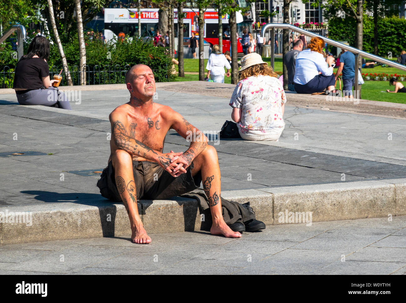 Man with body tattoos taking the sun in Galway, Ireland Stock Photo
