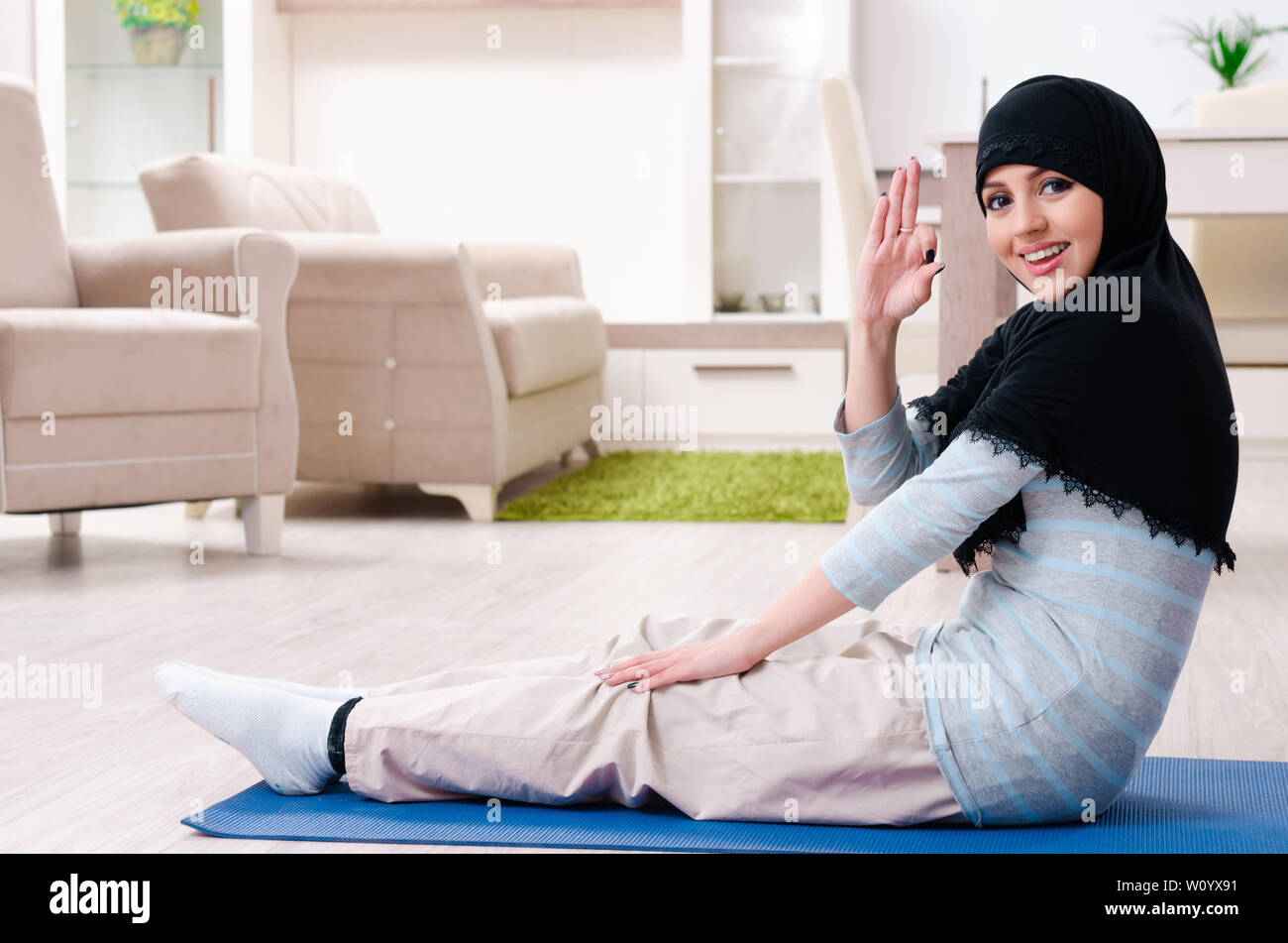 Young woman in hijab doing exercises at home Stock Photo - Alamy