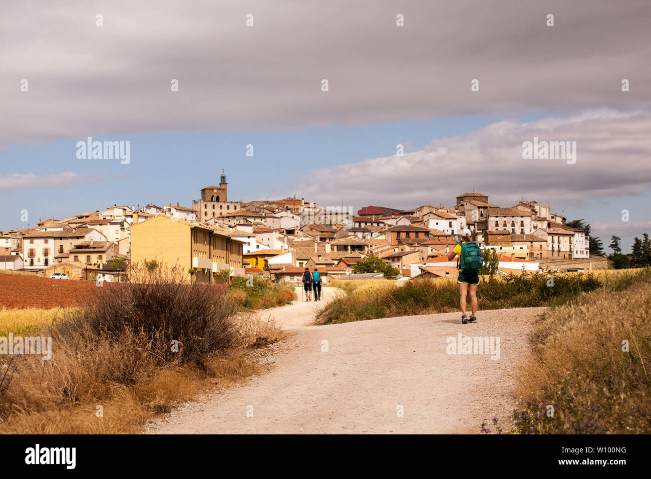 Woman pilgrim walking in the Spanish countryside on the Camino de Santiago the way of St James approaching the village of Cirauqui Navarra Spain Stock Photo