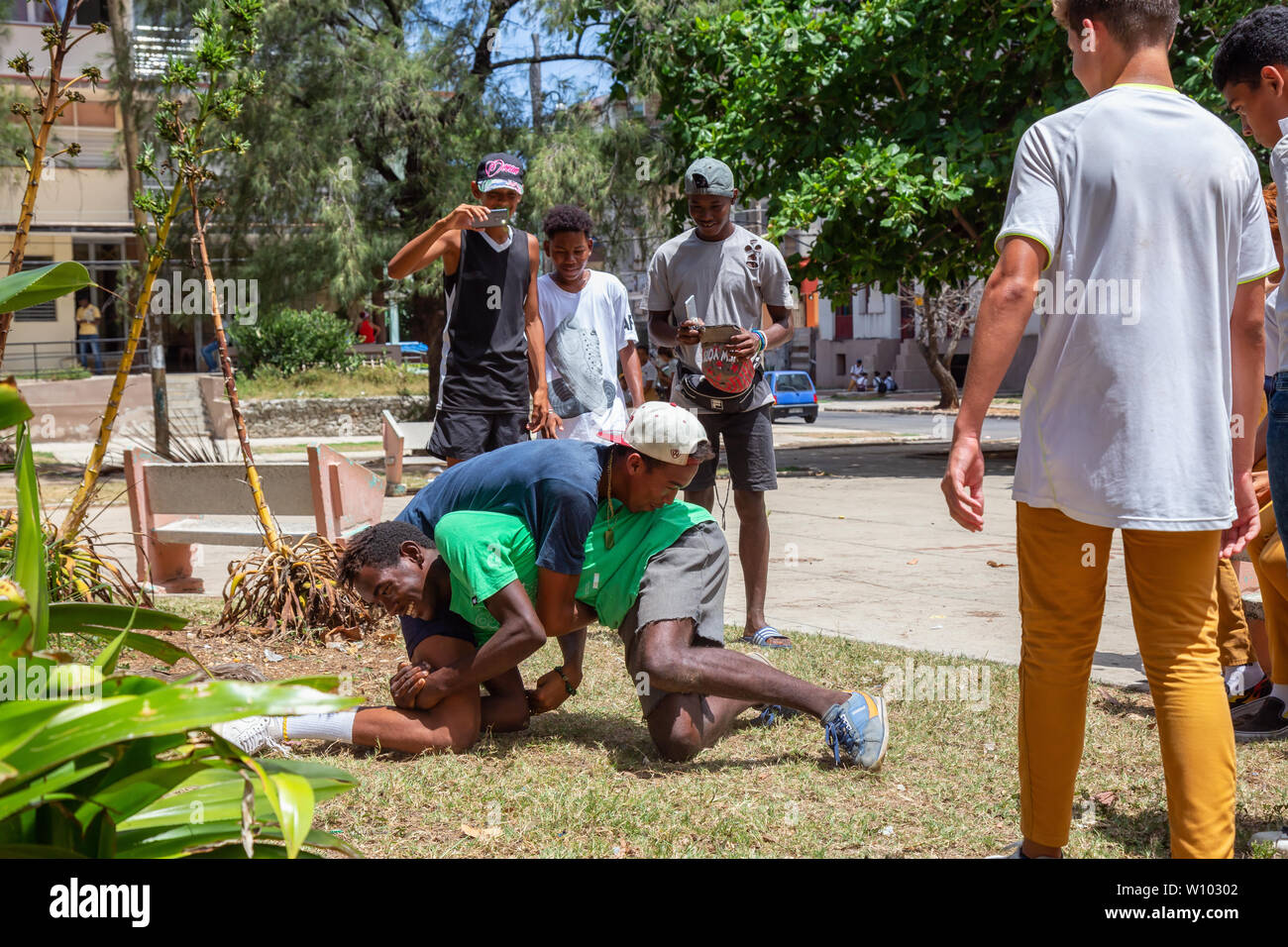 Havana, Cuba - May 14, 2019: Young Teenagers wrestling and having fun in a public square during a hot sunny day. Stock Photo