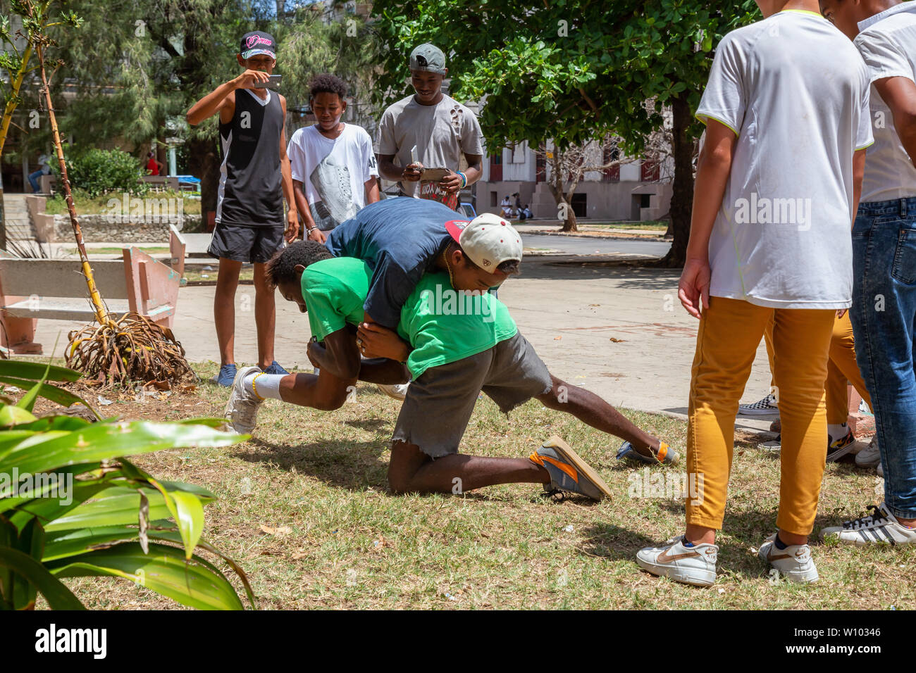 Havana, Cuba - May 14, 2019: Young Teenagers wrestling and having fun in a public square during a hot sunny day. Stock Photo