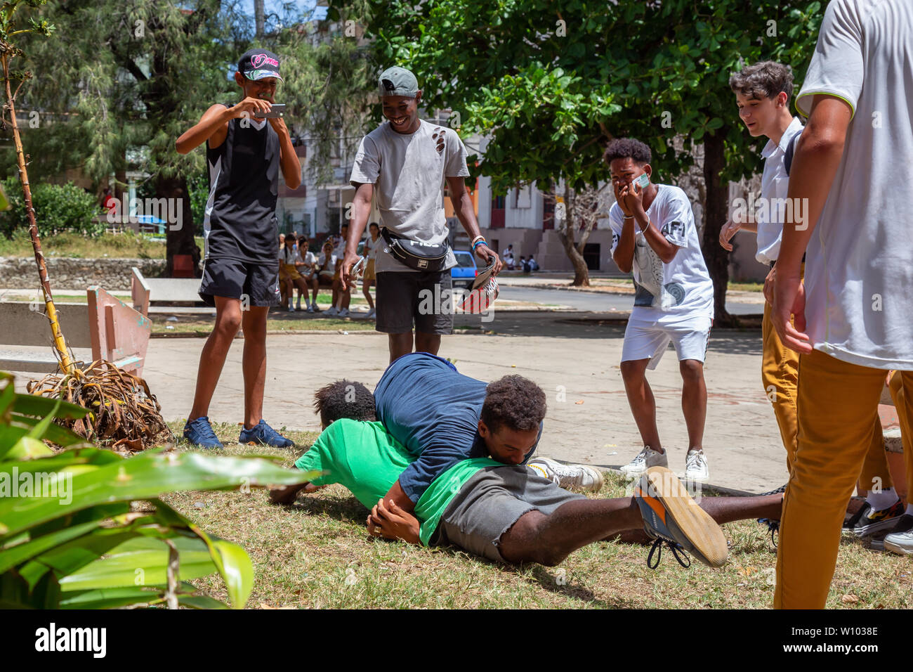 Havana, Cuba - May 14, 2019: Young Teenagers wrestling and having fun in a public square during a hot sunny day. Stock Photo