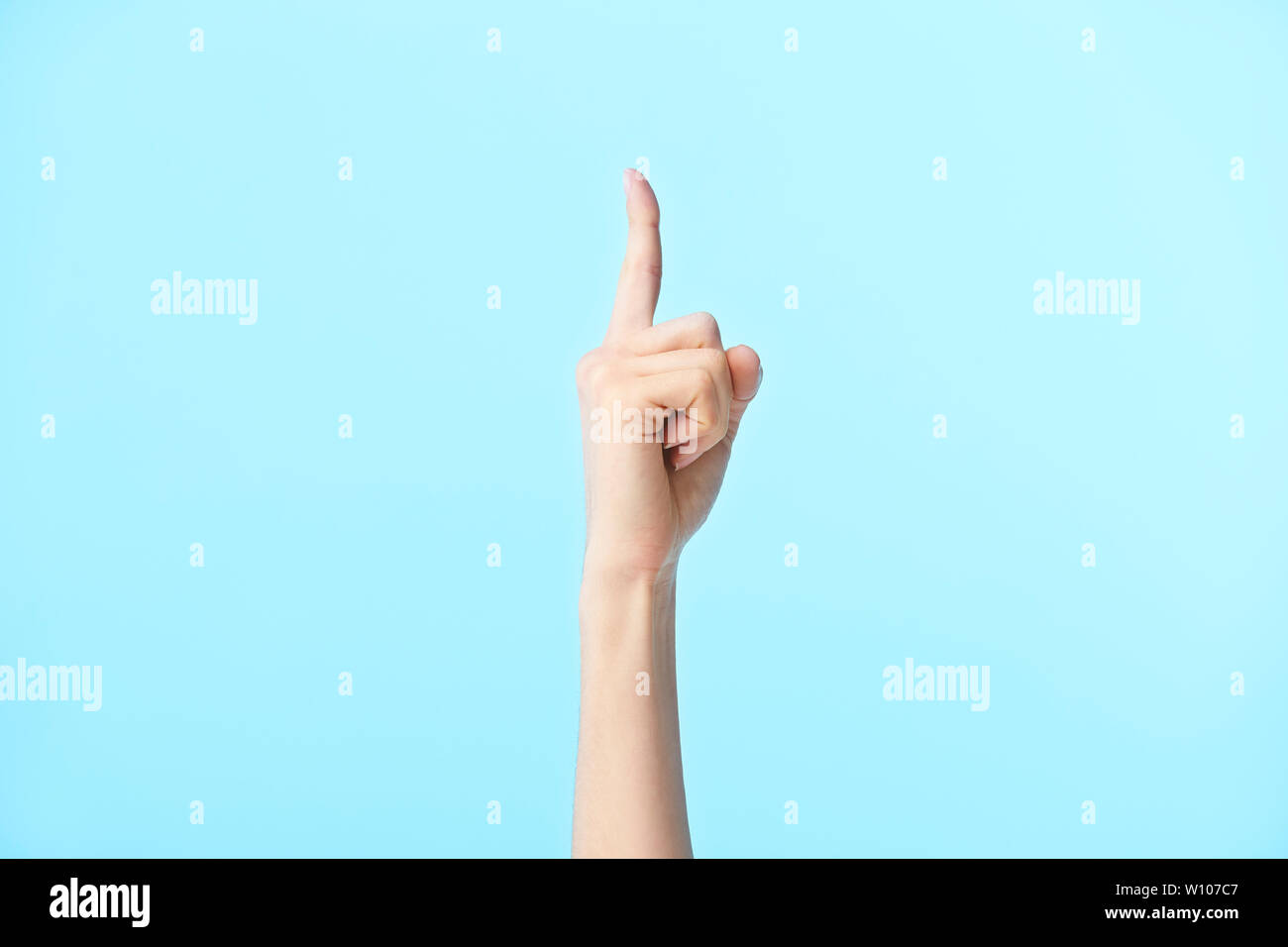 human hand showing number one, isolated on blue background Stock Photo